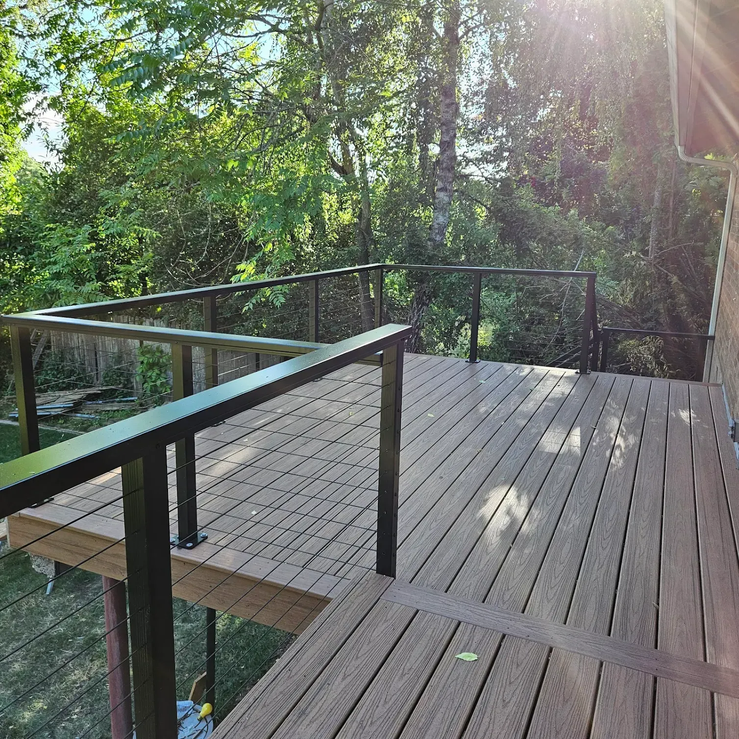A wooden deck with a metal railing and trees in the background.