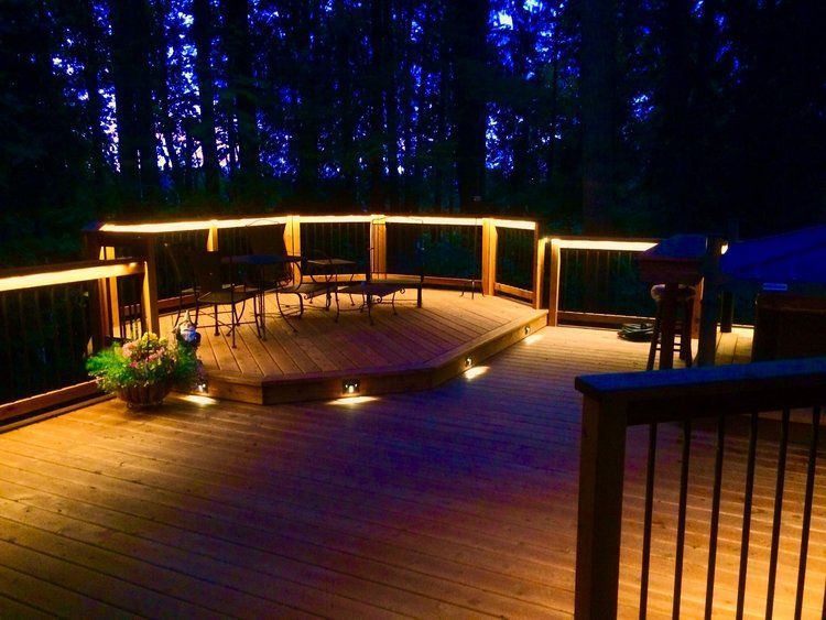 A house with a deck and stairs lit up at night