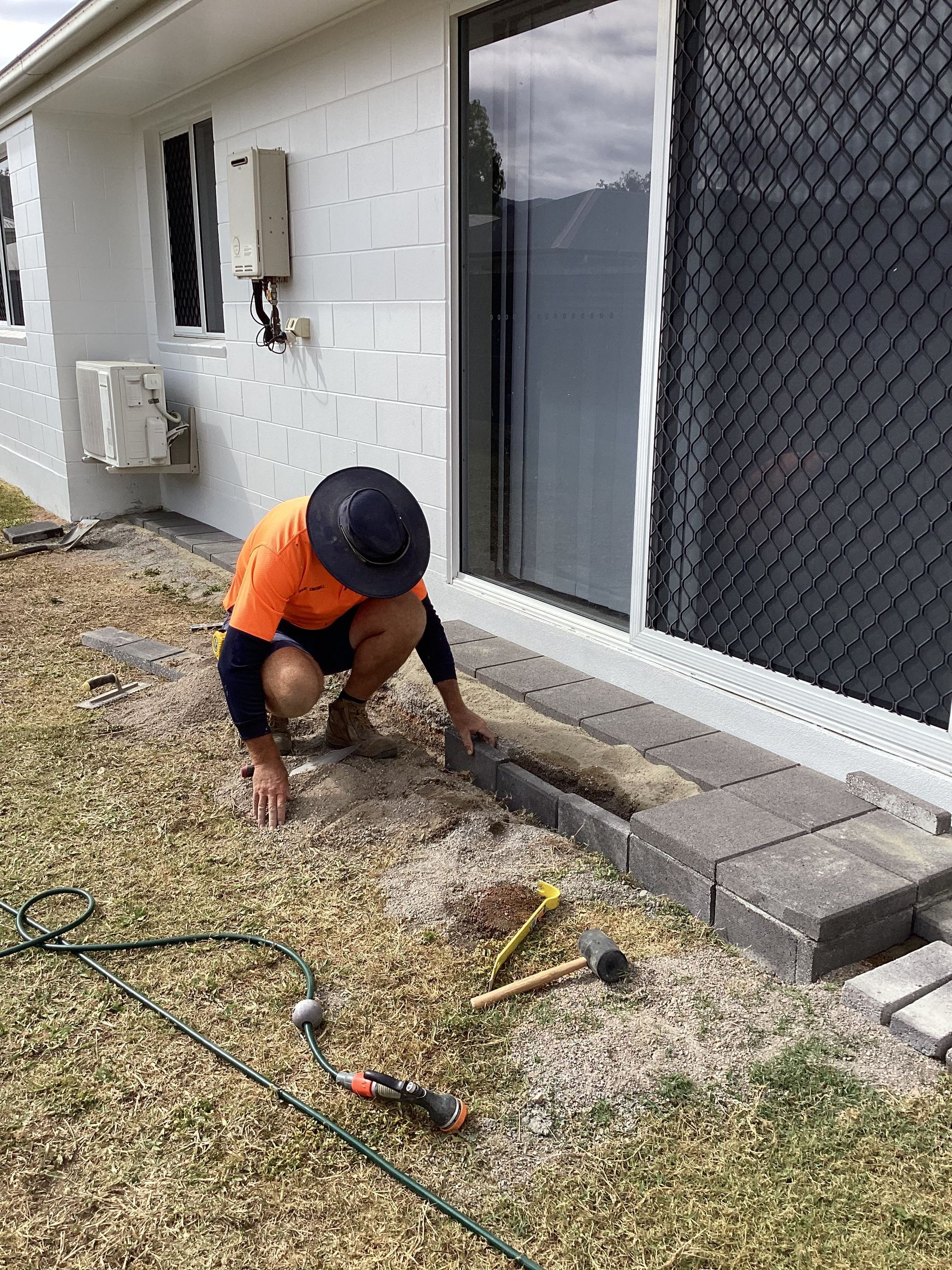 Person Installing Paving Stones Next to a Sliding Glass Door — My Handyman Townsville In Garbutt, QLD
