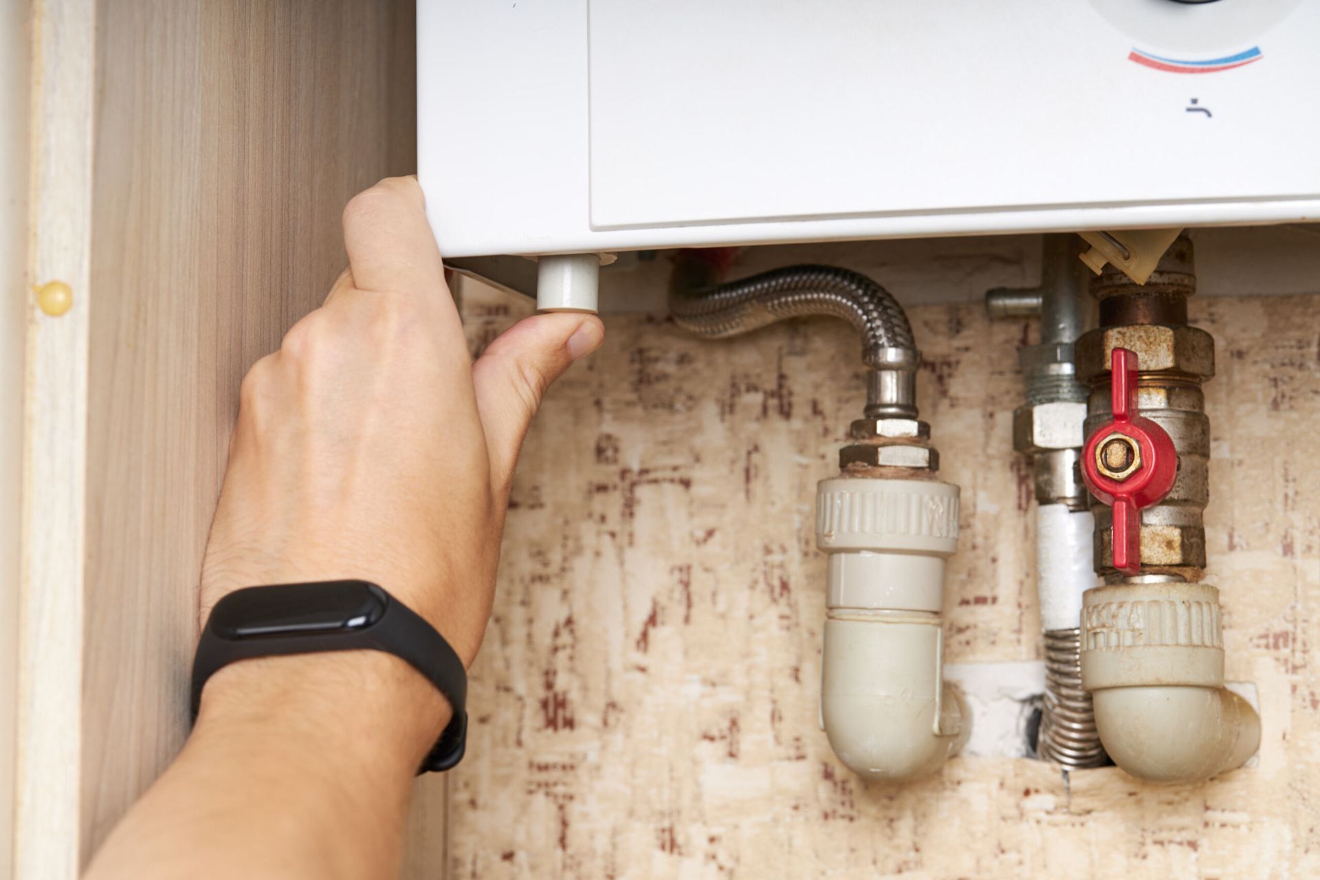 Hand Adjusting a Boiler Control Panel with Exposed Pipes and A Red Valve Underneath — My Handyman Townsville In Garbutt, QLD