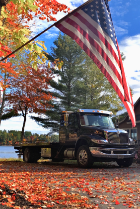 A truck is parked next to a large American flag | Collins Enterprises