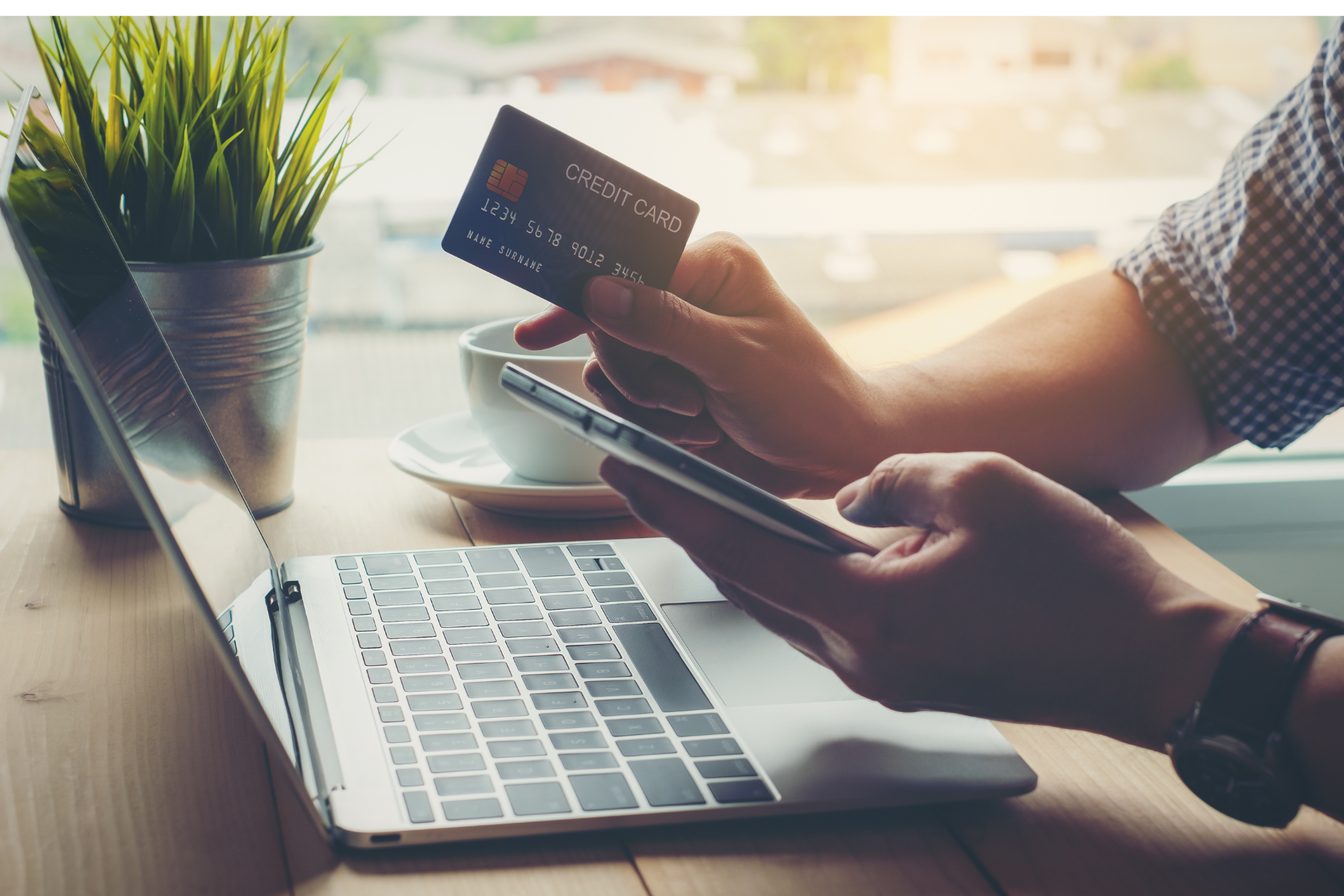 A person is holding a credit card and using a laptop computer.