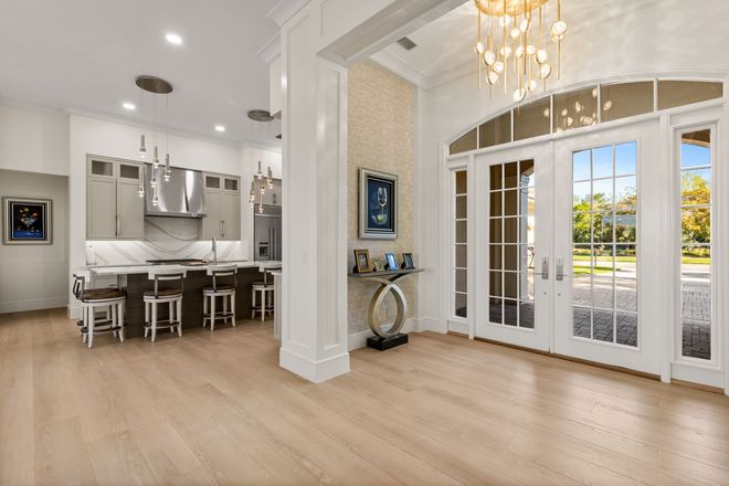 Spacious interior with kitchen, French doors, chandelier, and light wood flooring.