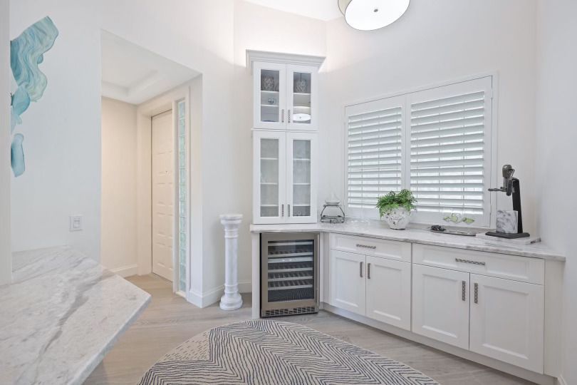 A kitchen with white cabinets , a refrigerator and a rug.