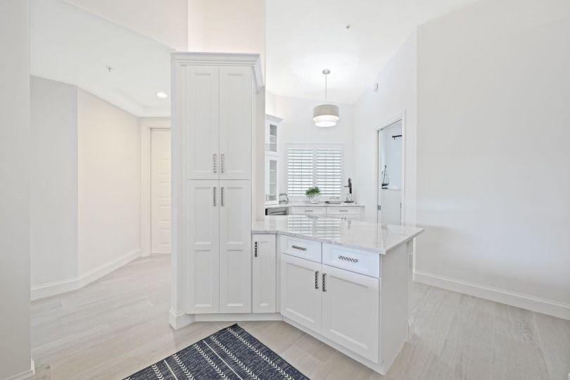 A kitchen with white cabinets and a rug on the floor.