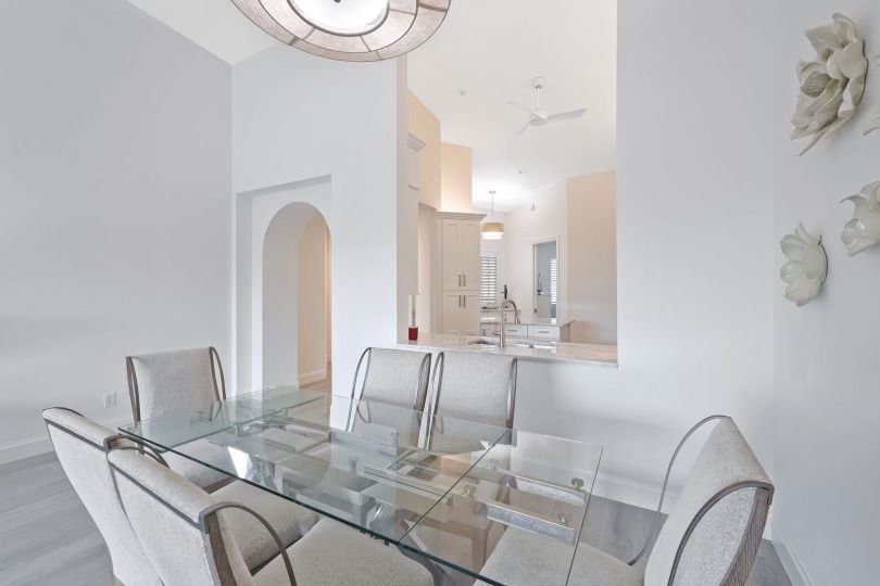 A dining room with a glass table and white chairs