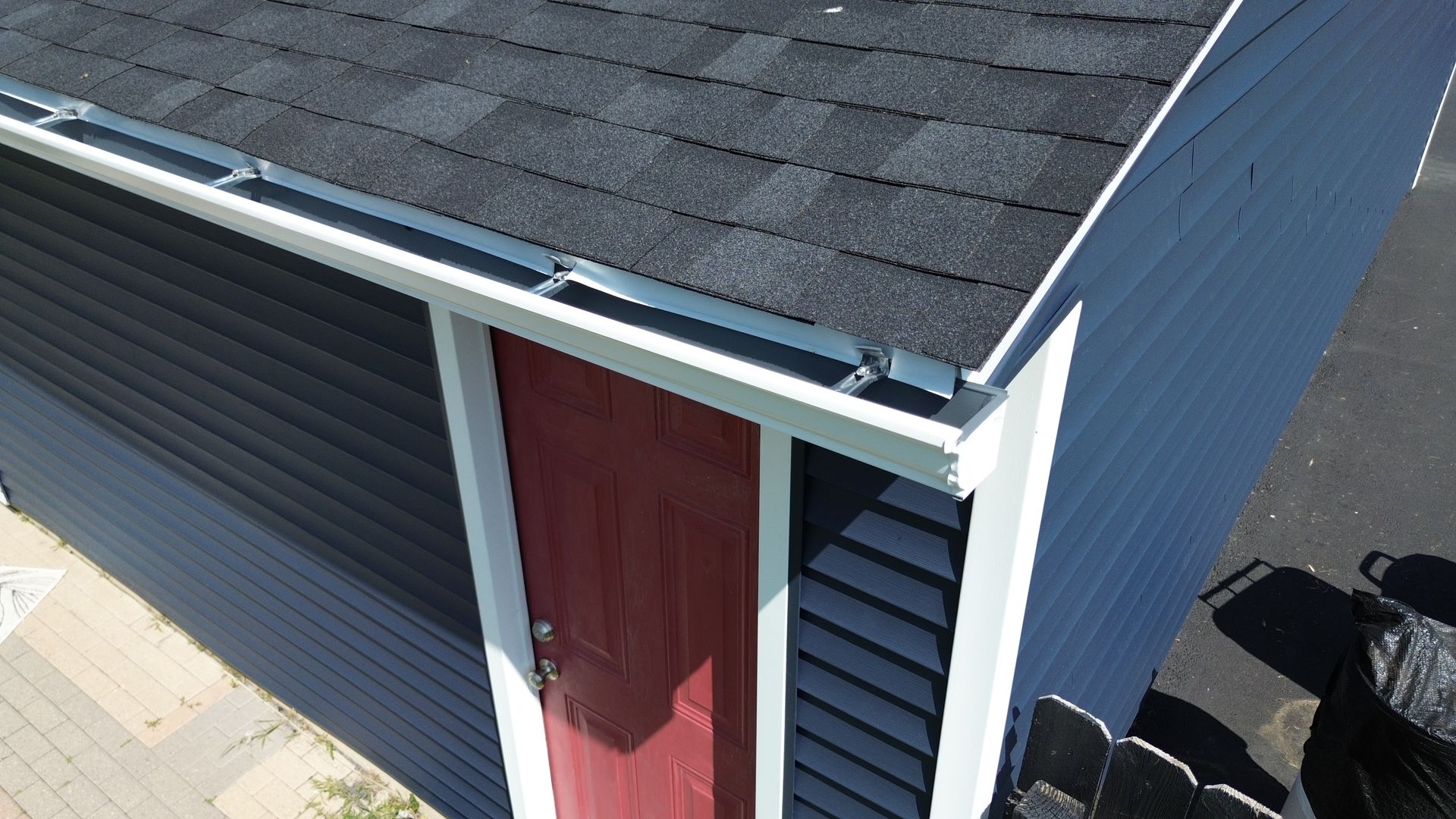 A man is standing on top of a roof looking at it.