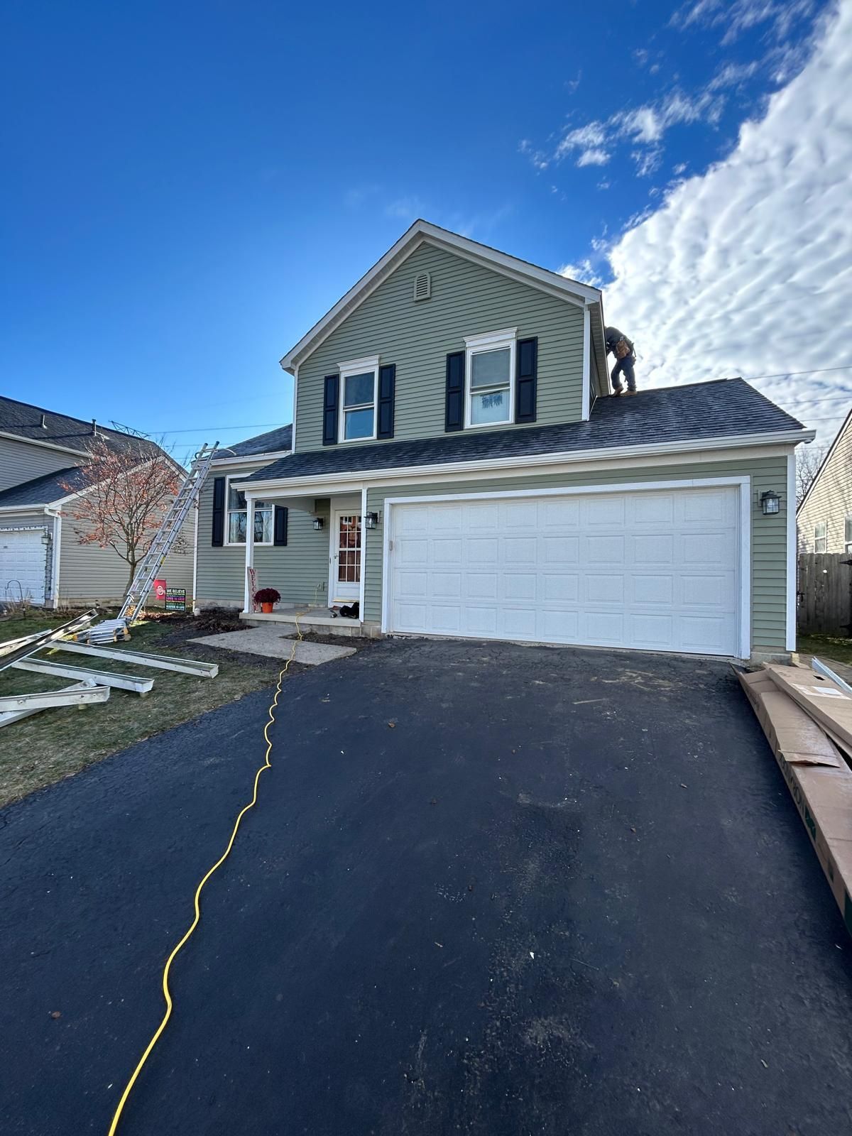 A man is standing on top of a roof looking at it.