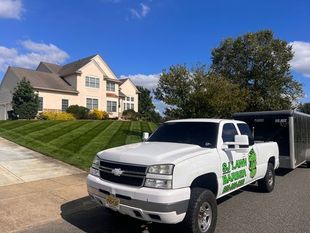 White pickup truck with trailer parked in front of a house with freshly cut lawn; White pickup truck with trailer parked in front of a house with freshly cut lawn;