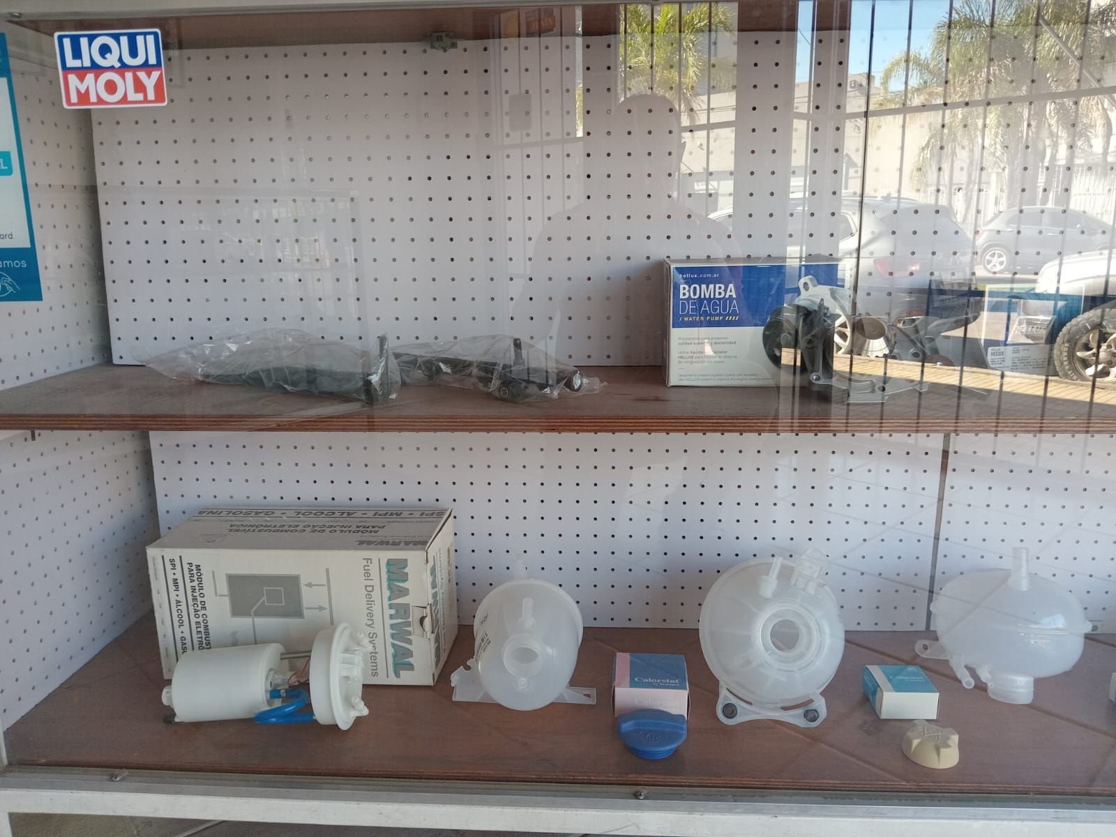 Estanterías que muestran piezas de automóviles para la venta, incluidos filtros, tanques y otros componentes.