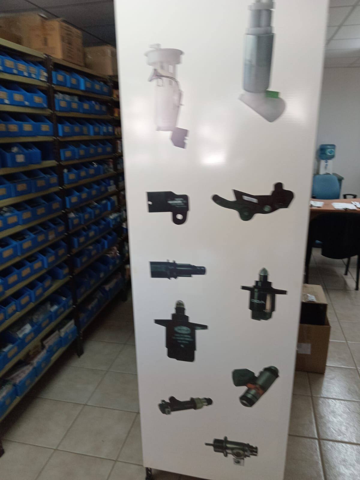 Tablero de exhibición con piezas de automóviles en una tienda de repuestos para automóviles, estantes al fondo.