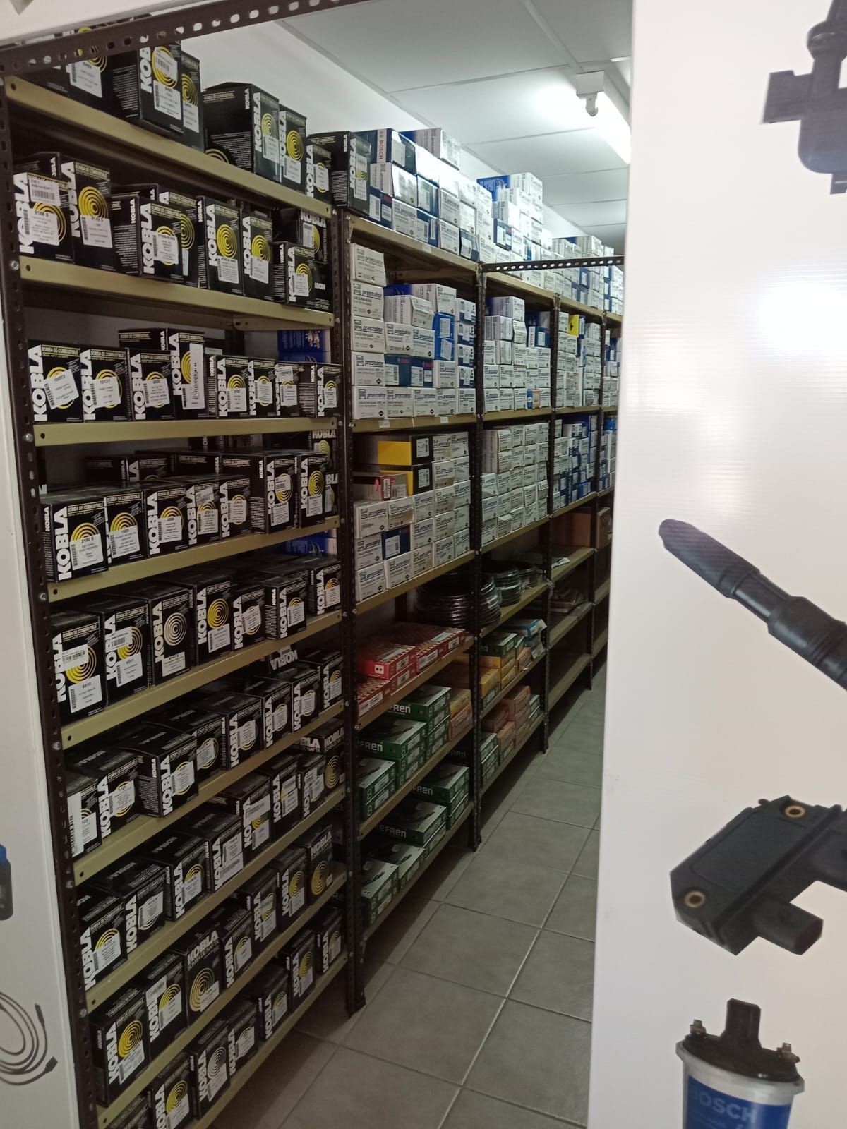 Estantes repletos de piezas de automóviles en un pasillo estrecho.