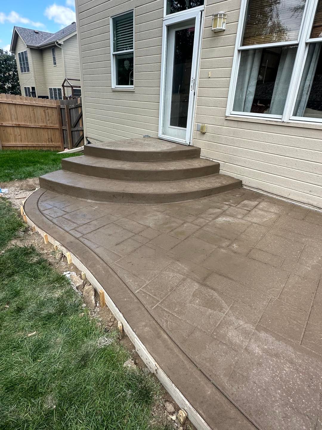 A concrete patio with stairs leading up to a house.