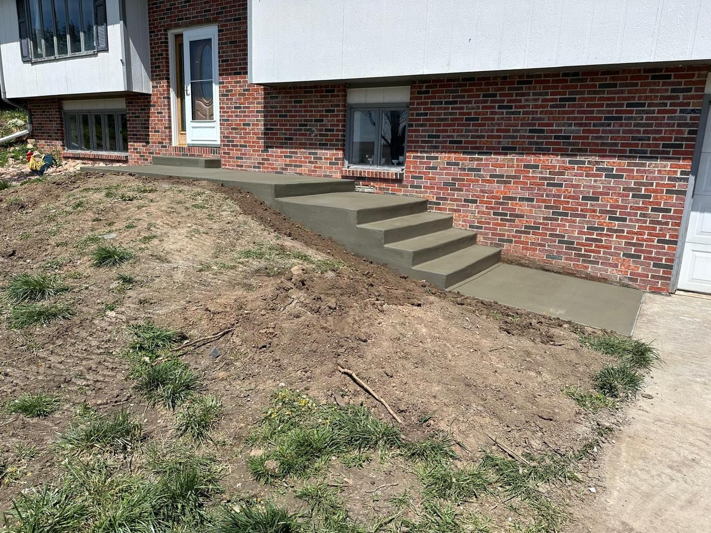 A brick house with concrete steps leading up to it.