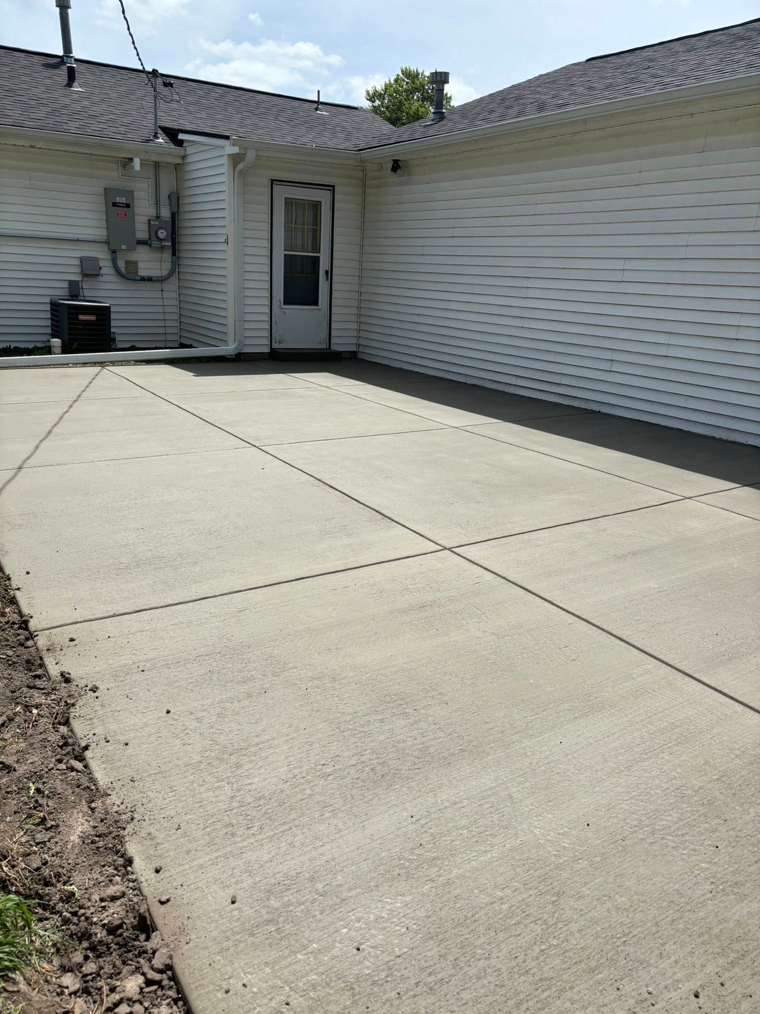 A concrete driveway leading to a white house with a garage door.