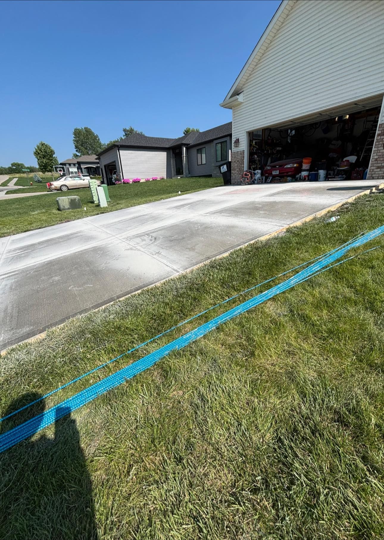 A concrete driveway is being painted blue in front of a house.