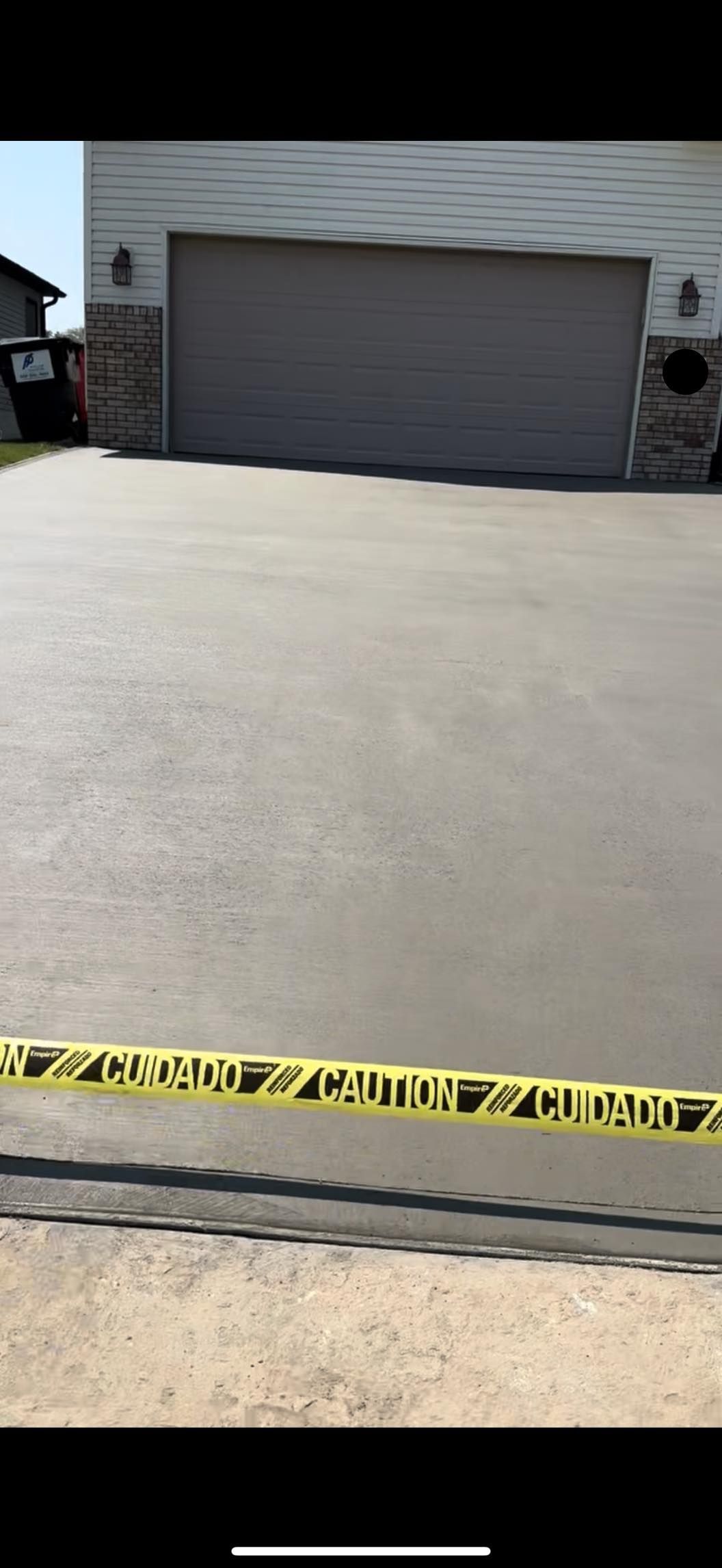 A driveway with a garage door and a yellow caution tape.