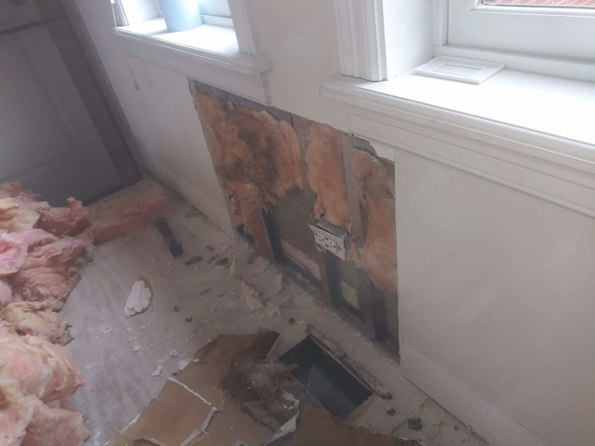 A room with a hole in the wall and a window.