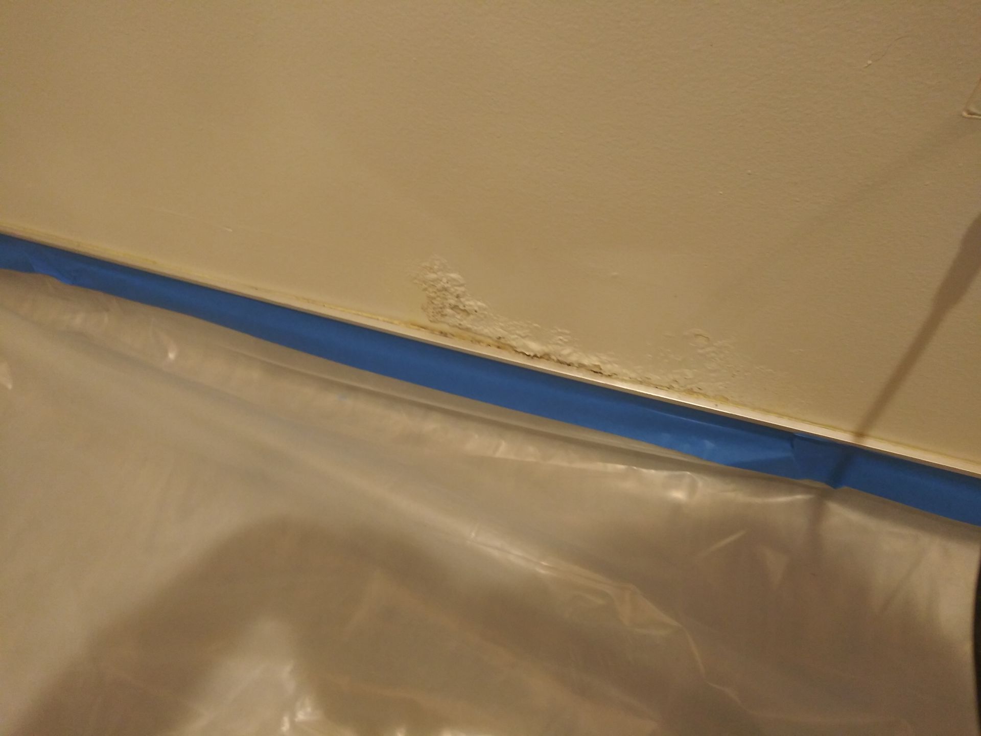 A white tile wall with a blue tape on it.