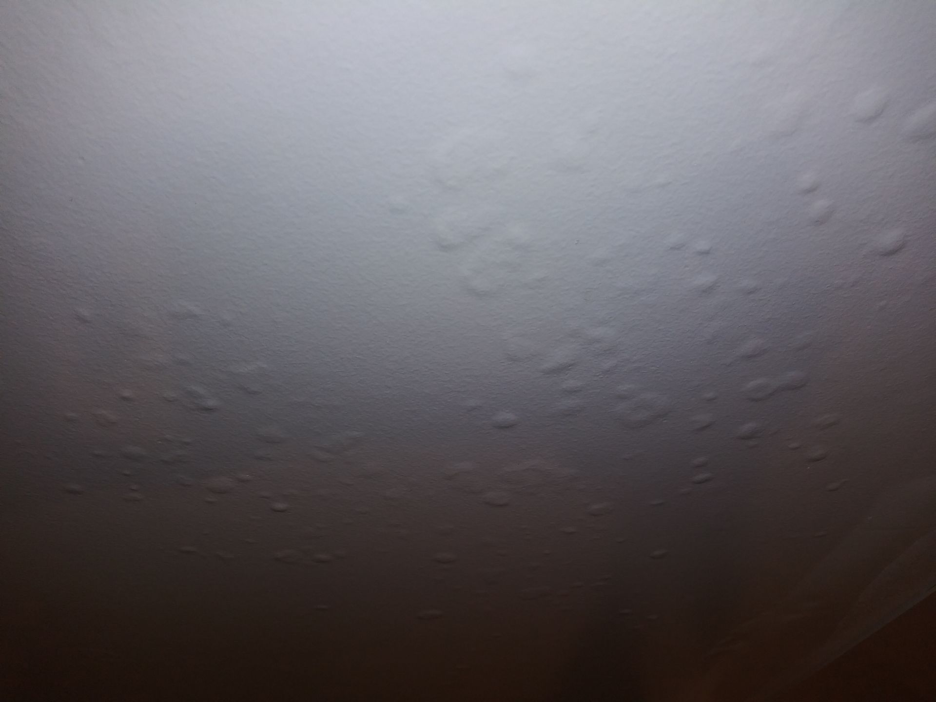A close up of a white wall with a lot of spots on it.