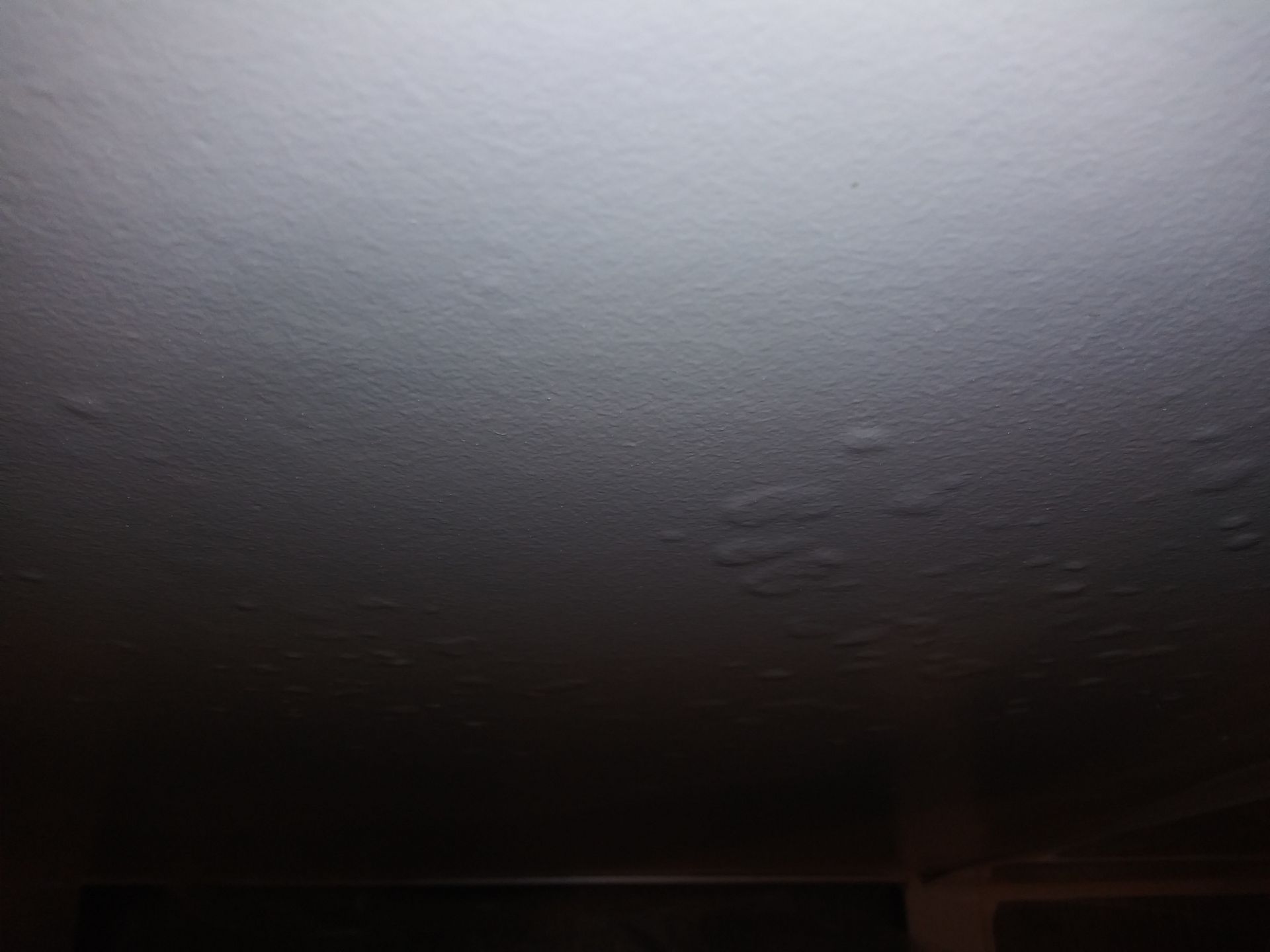 A close up of a white ceiling with water drops on it.