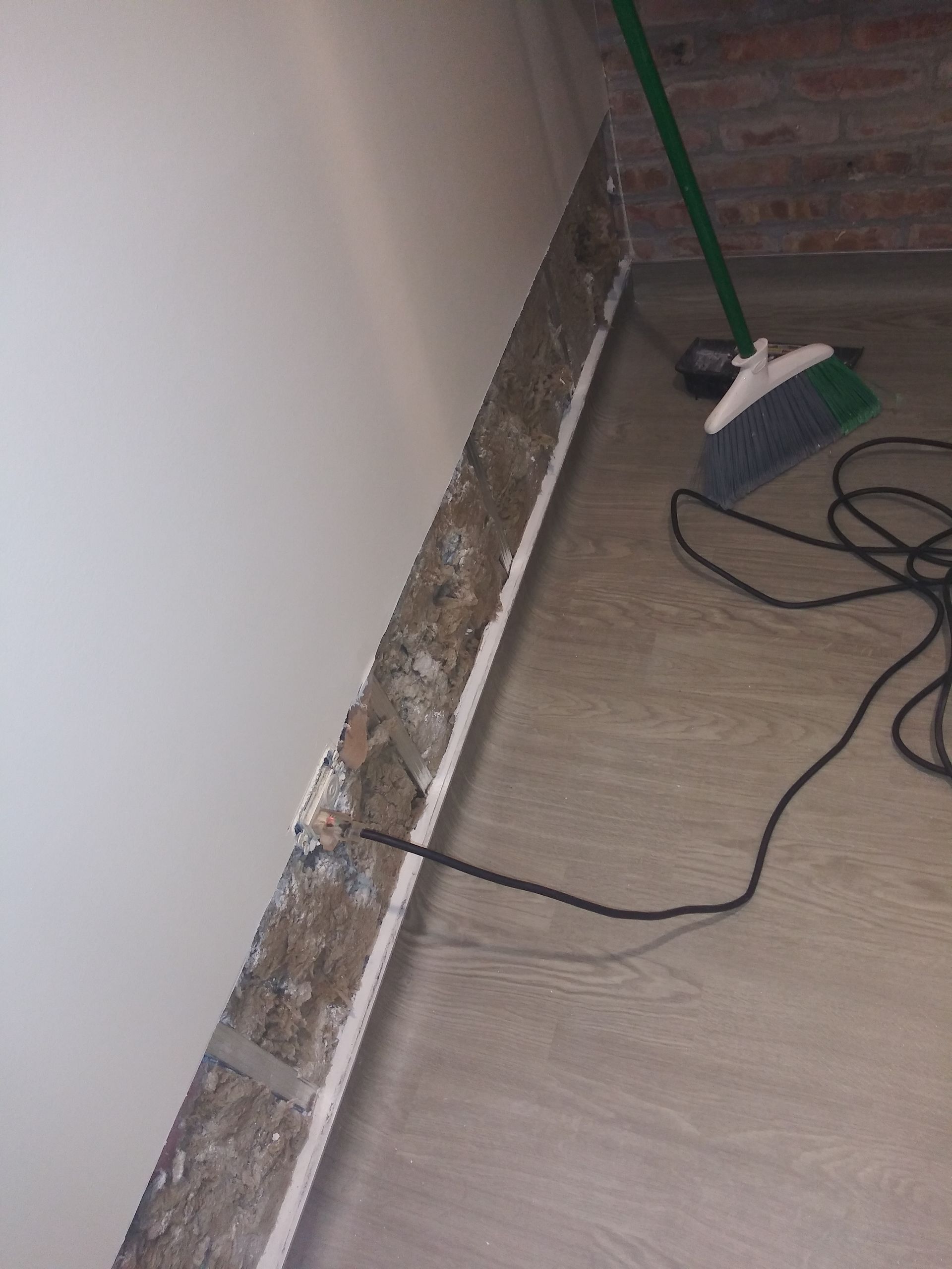 A broom is sitting on the floor next to a wall.