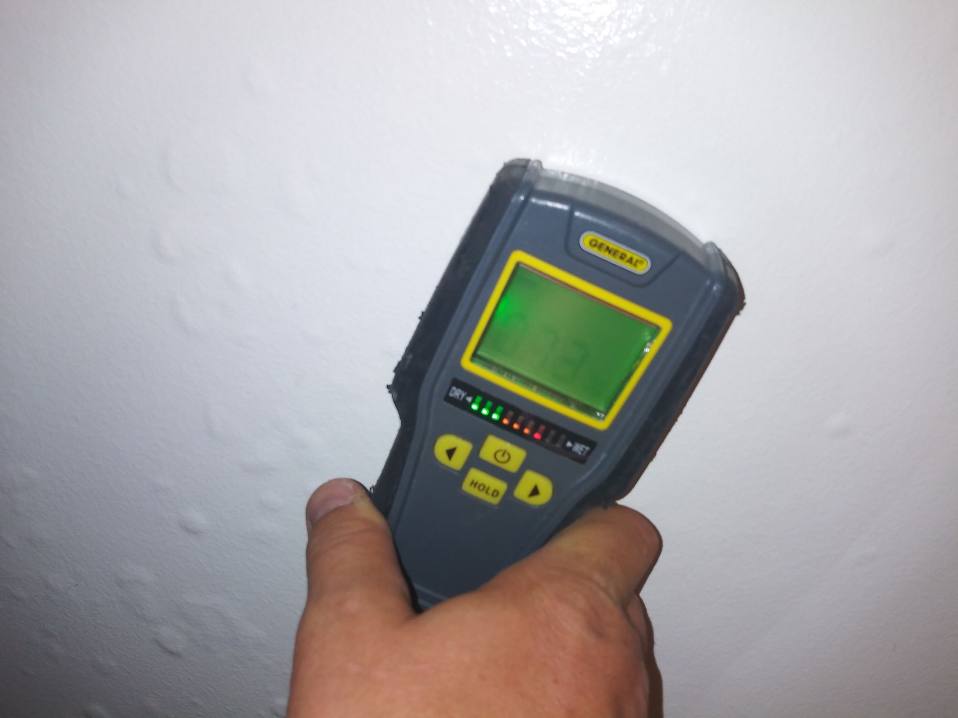 A person is holding a device with a green screen