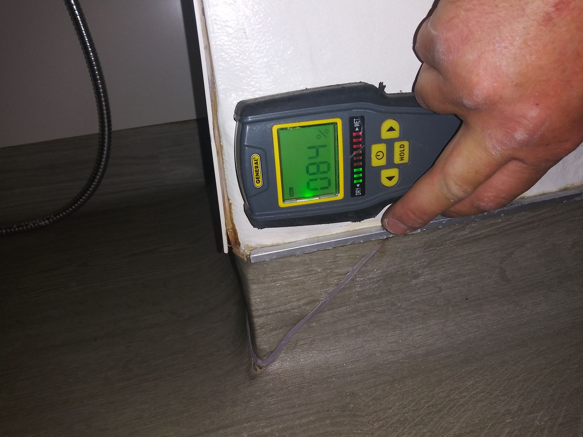 A person is measuring a wall with a device that reads 0.84