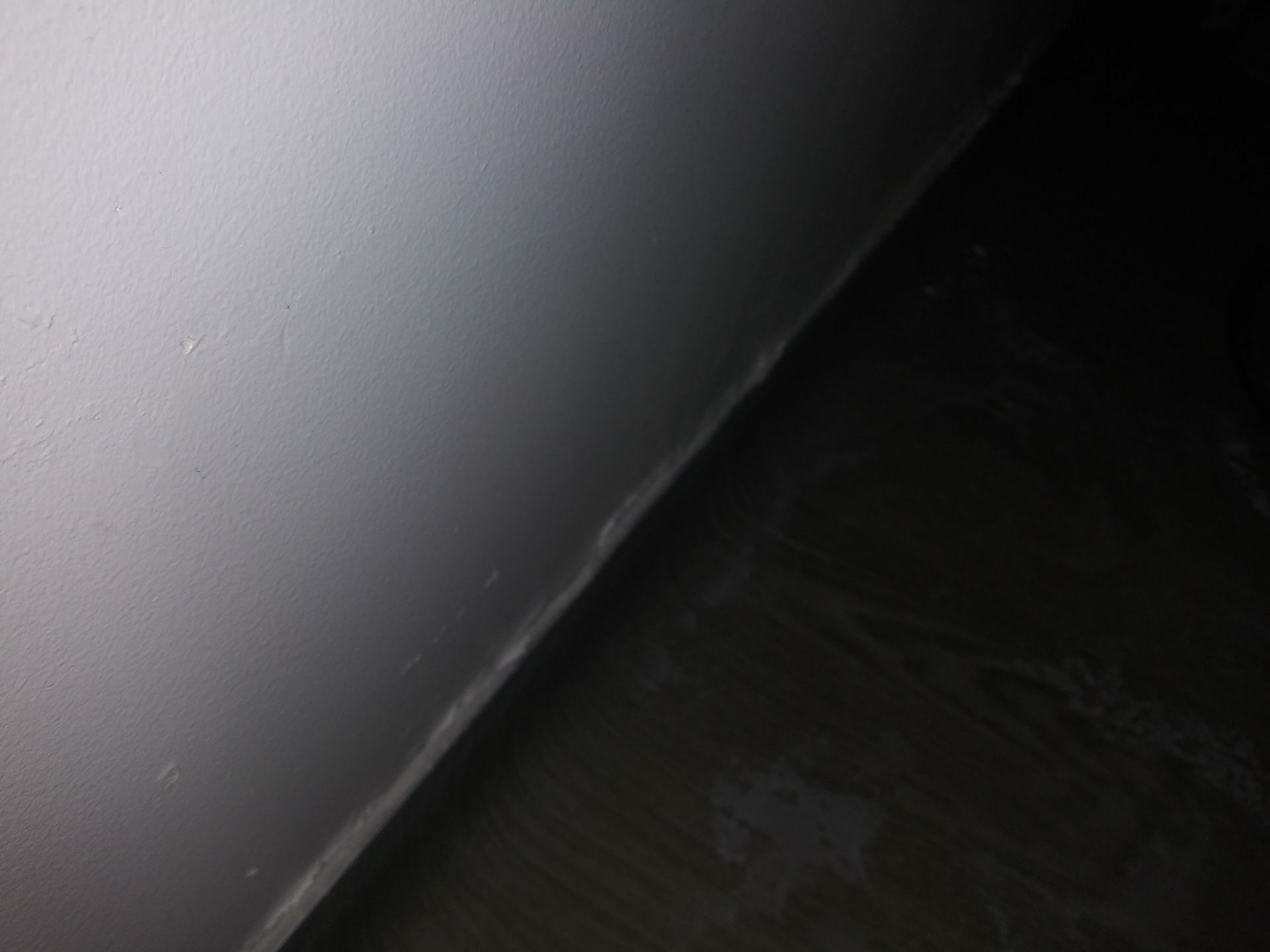 A close up of a white wall and a black floor.