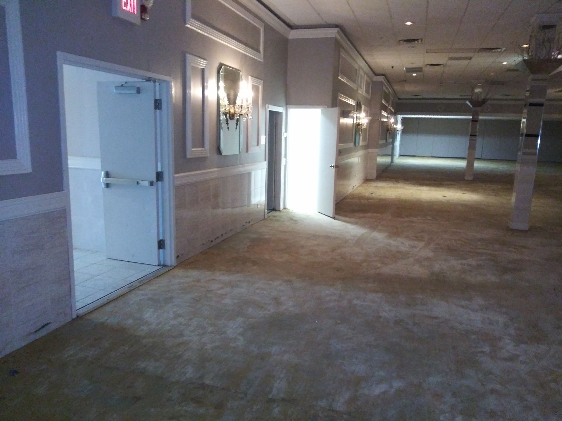 An empty hallway with a red exit sign on the wall
