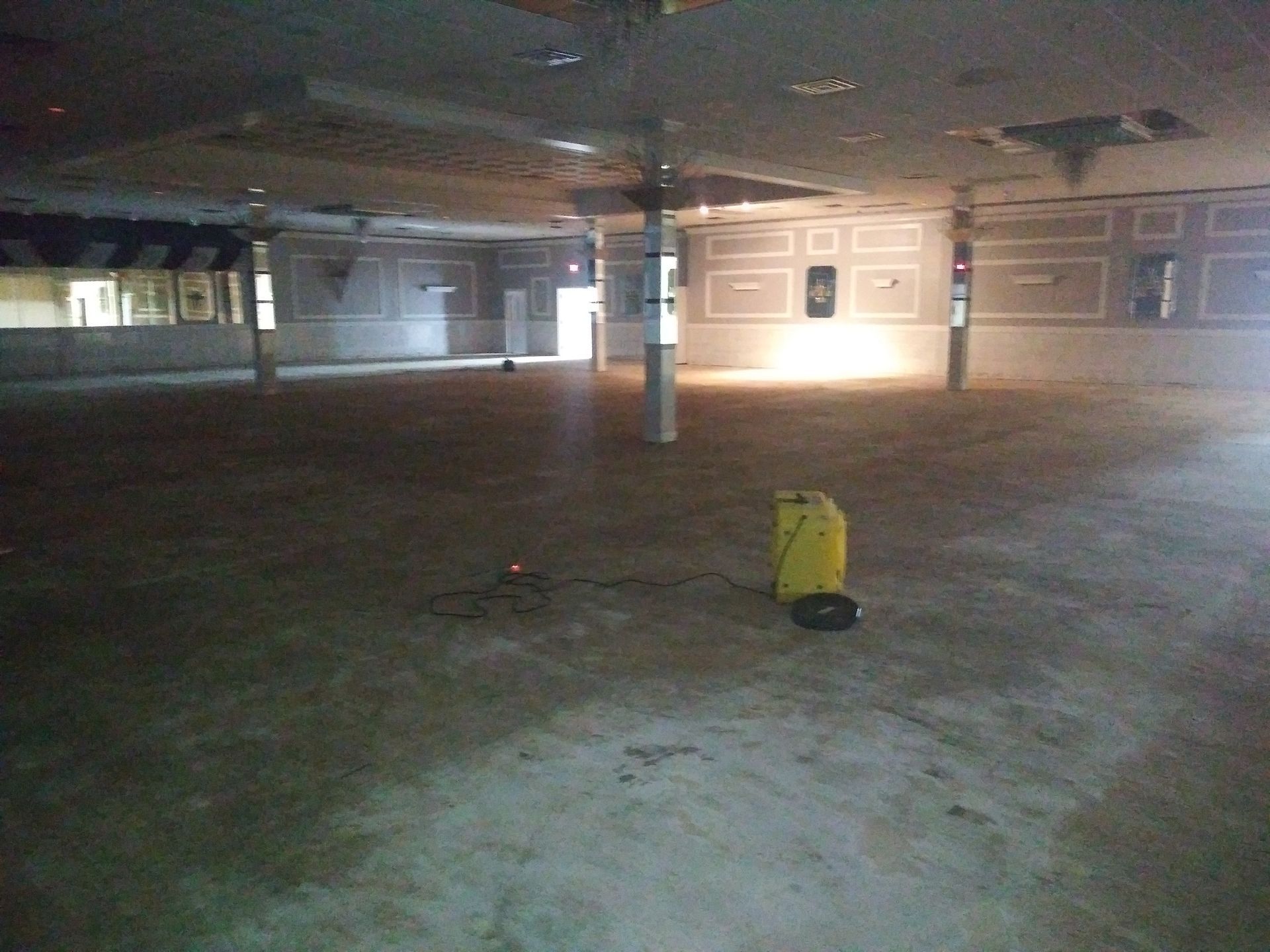 A large empty room with a yellow bucket on the floor