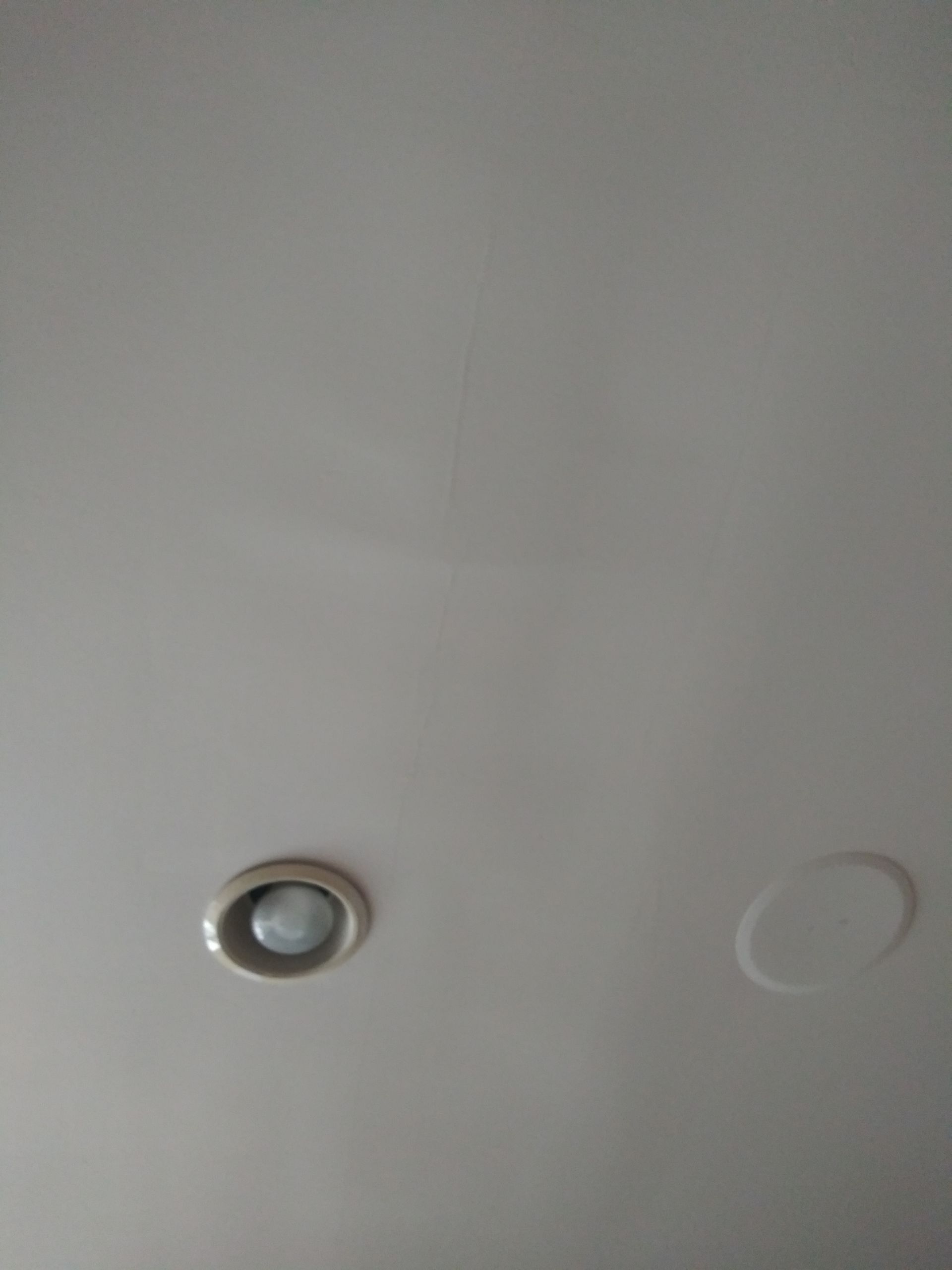 A white ceiling with a motion sensor on it.