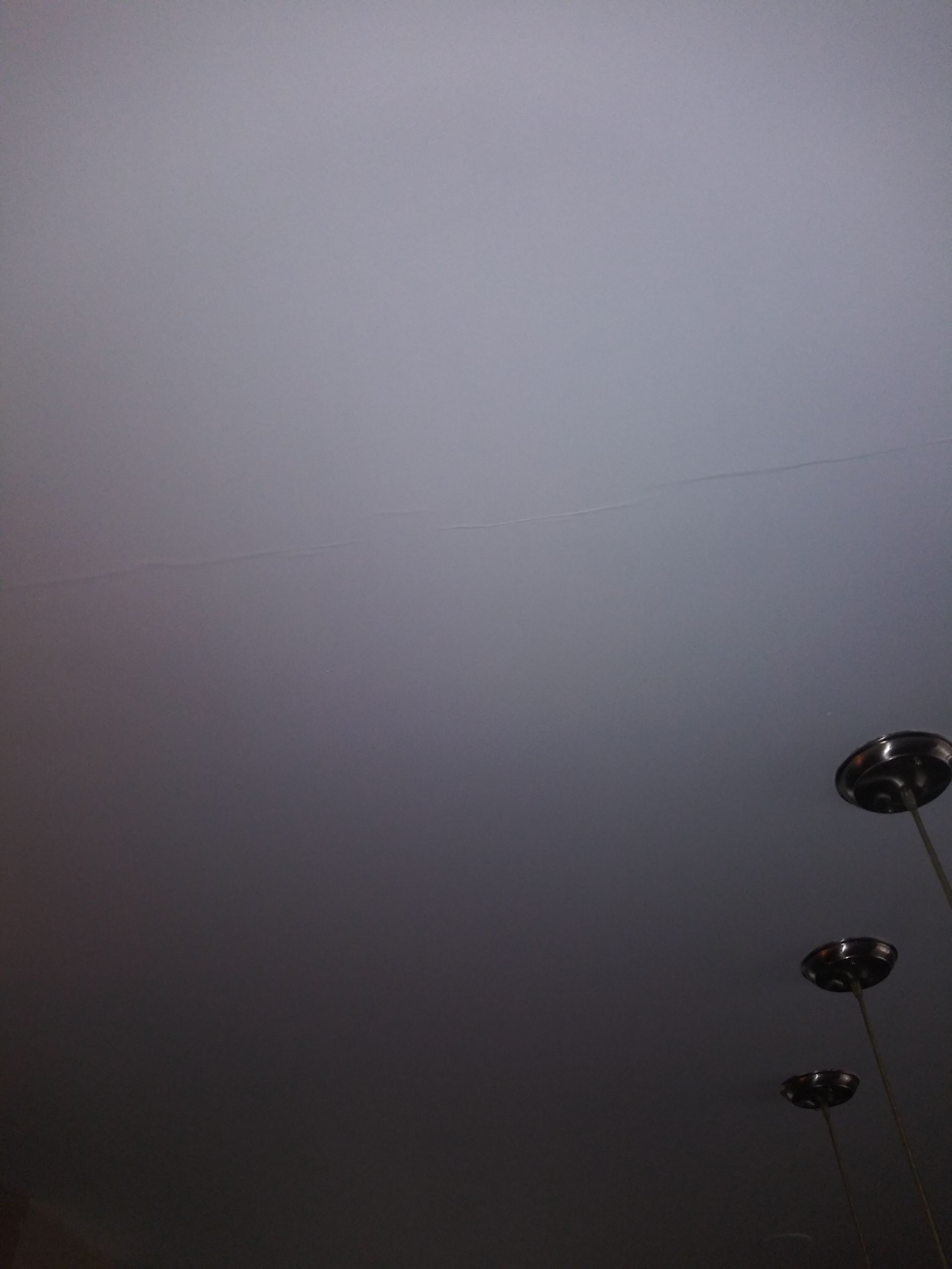 There are three lights hanging from the ceiling in the fog.