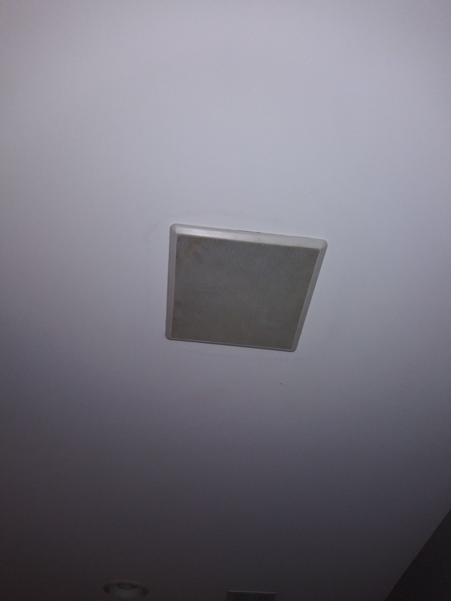 A square air vent is hanging from the ceiling of a room.