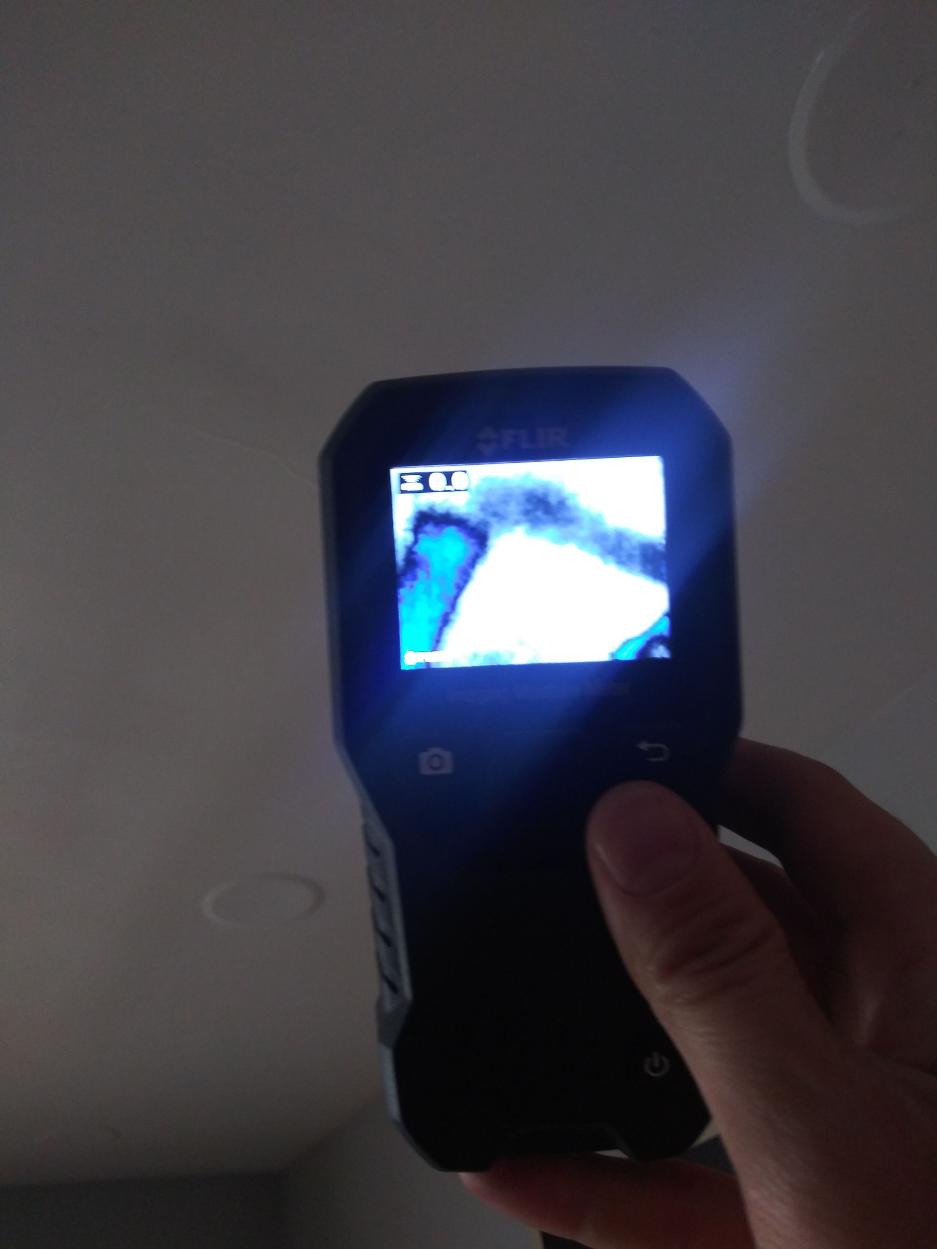 A person is holding a camera with a blue screen