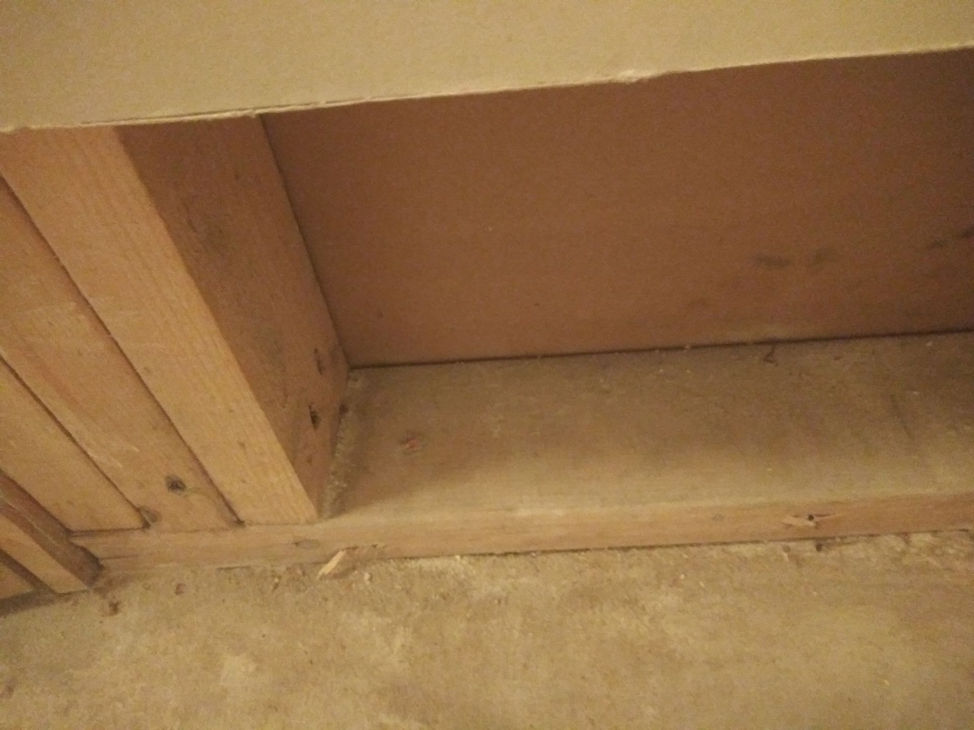 A wooden box is sitting on the floor next to a wall.