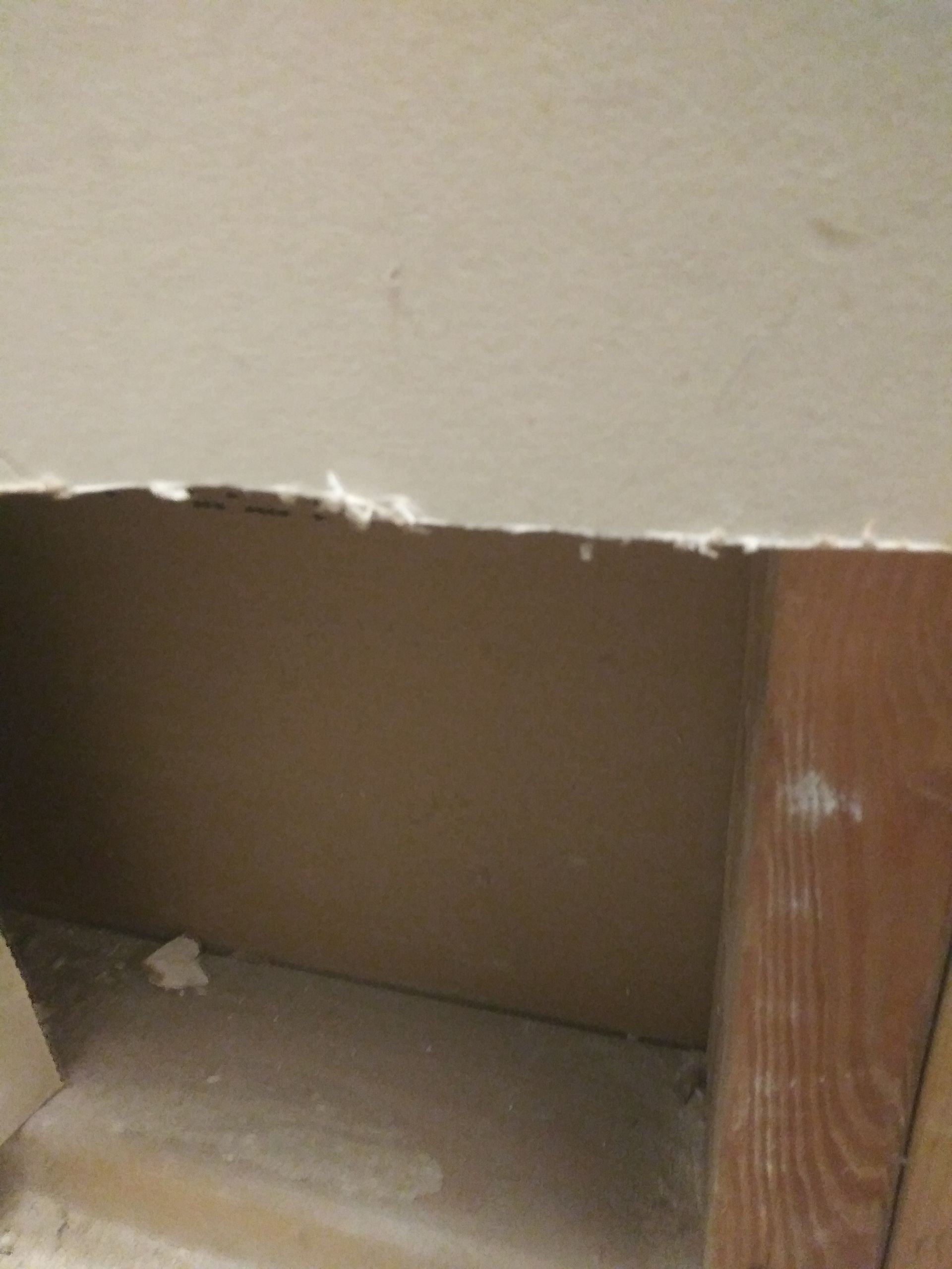 A corner of a wall with a hole in it.