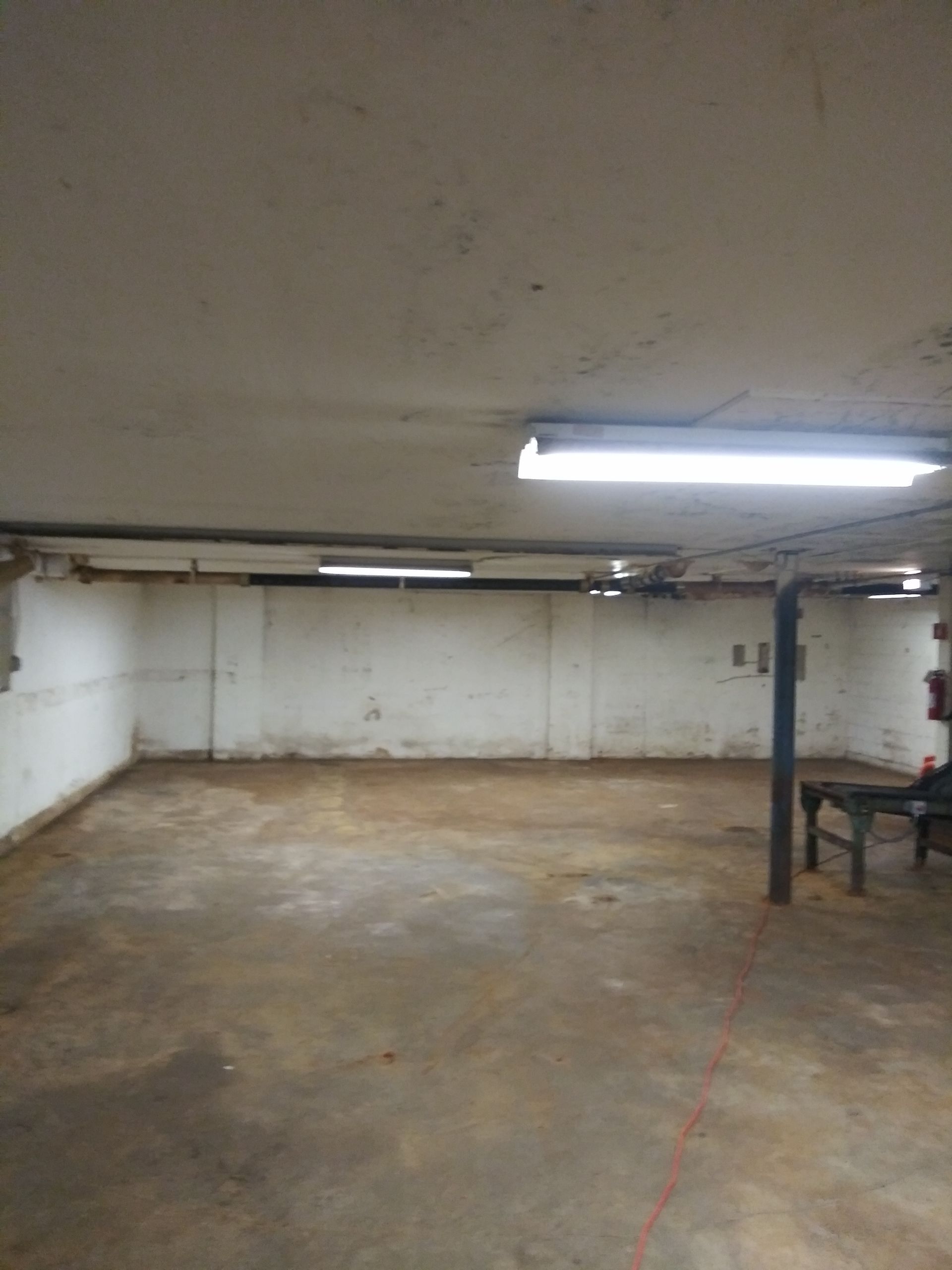 An empty basement with a table and chairs in it.