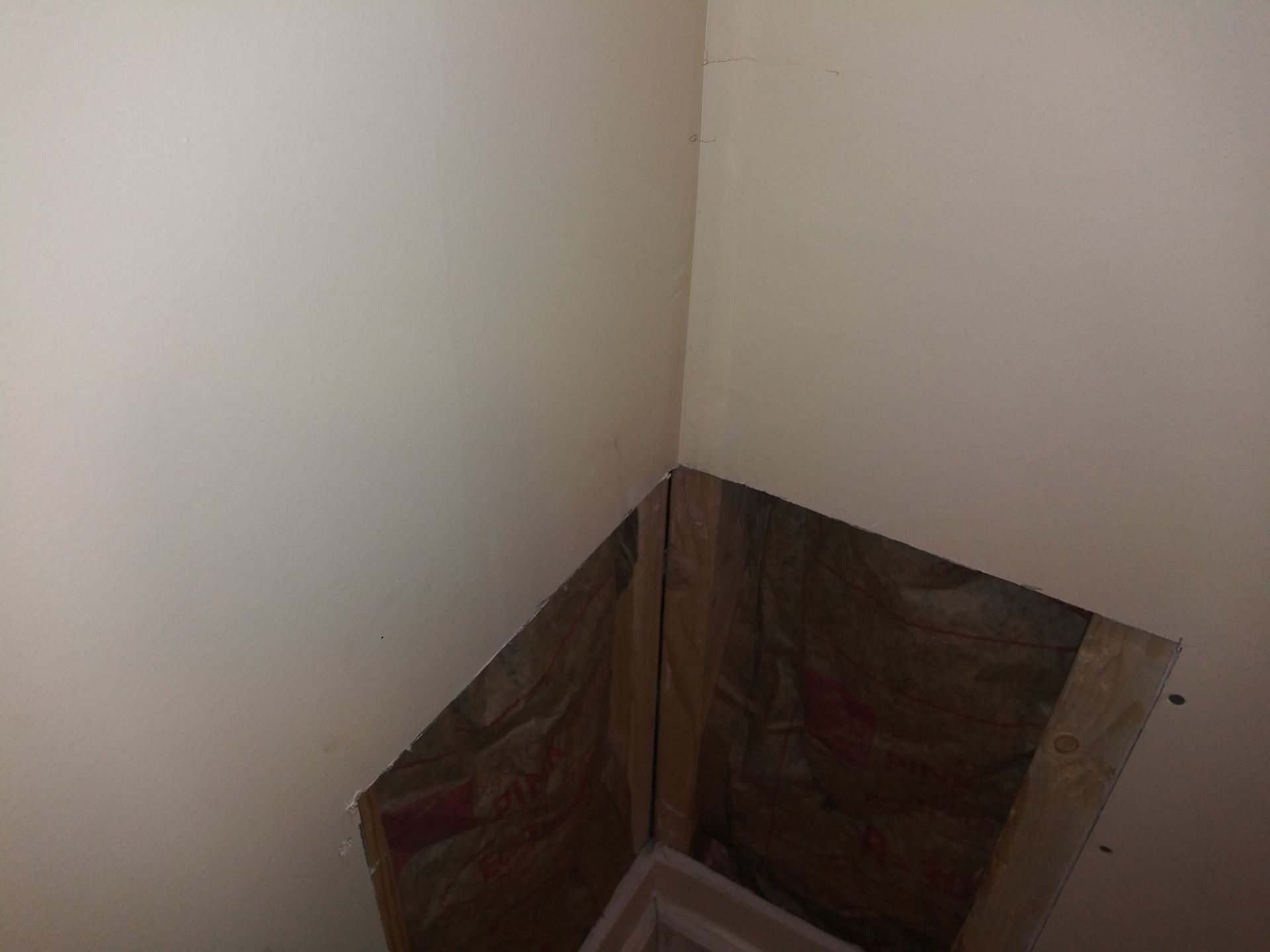A corner of a room with a hole in the wall.