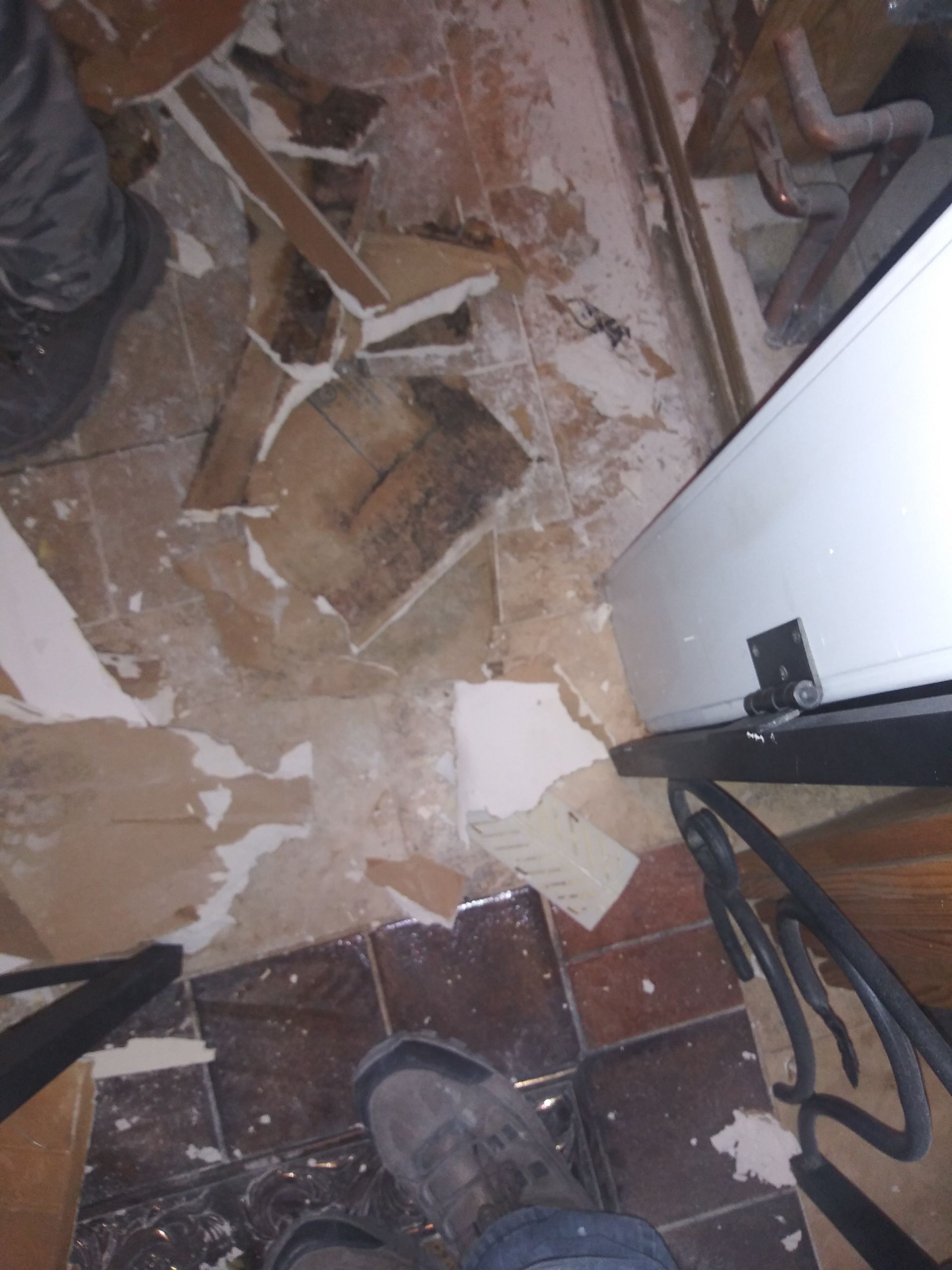 A person standing on a tiled floor next to a refrigerator