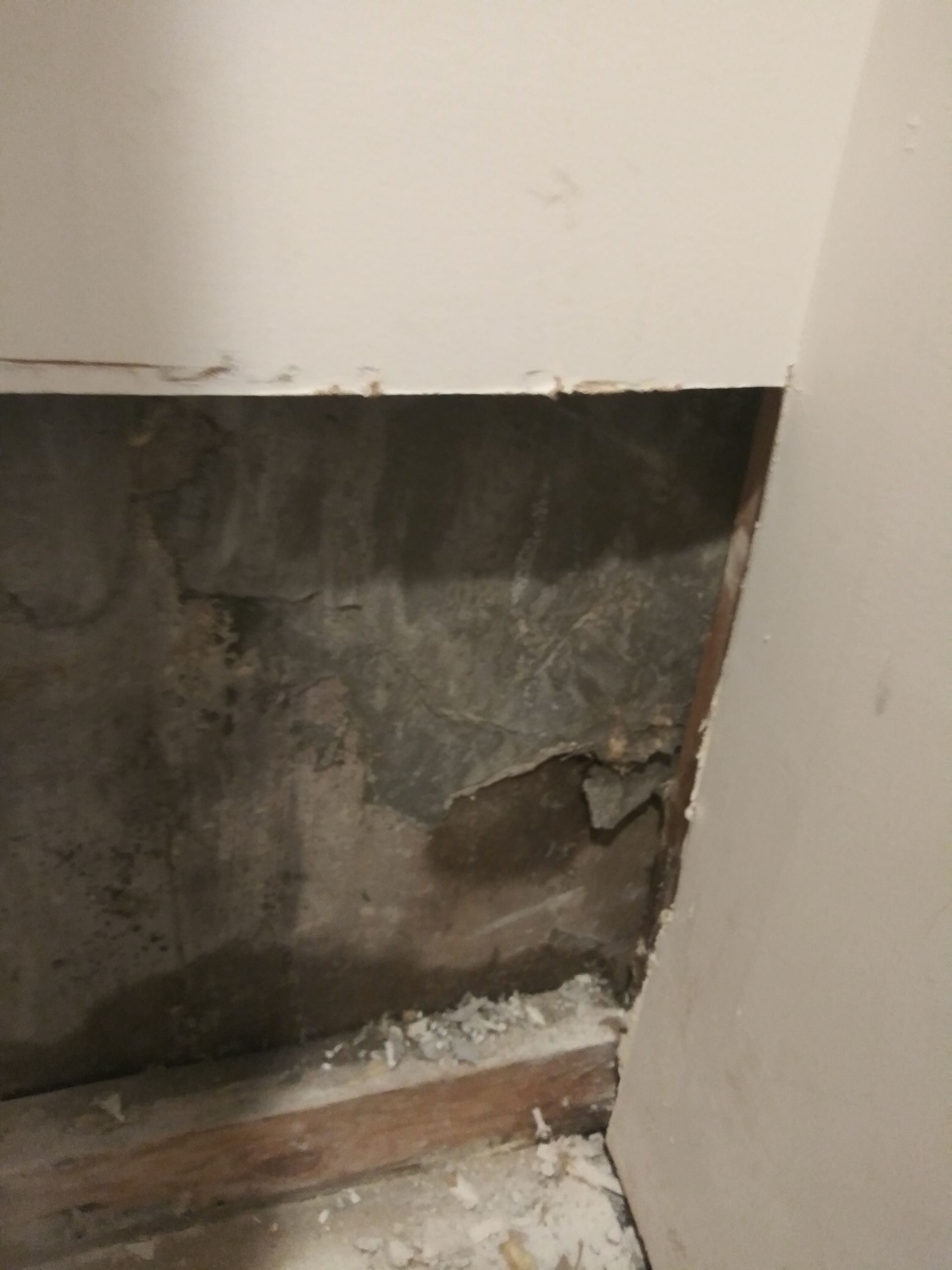 A corner of a room with a hole in the wall.