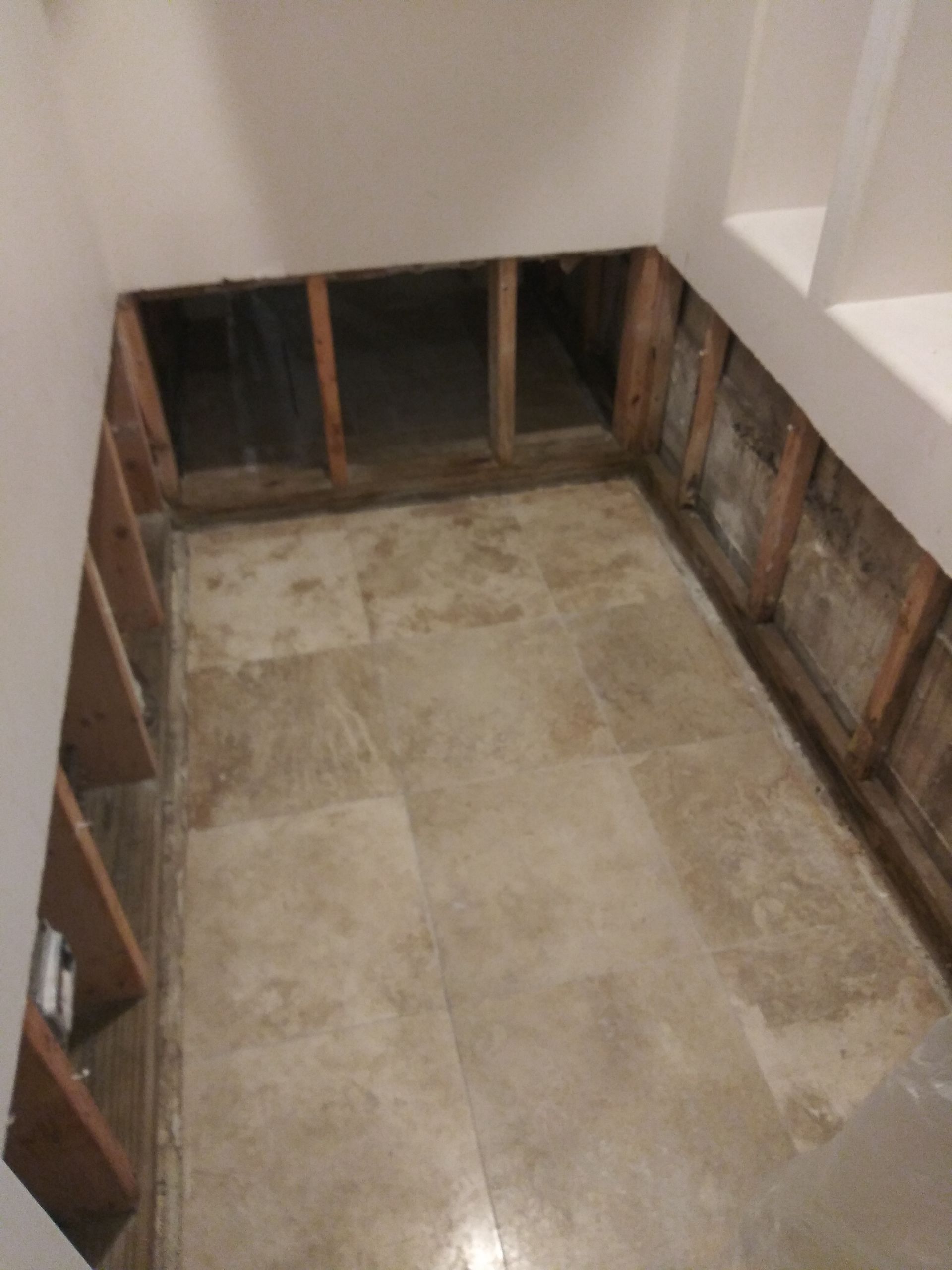 A room with a tiled floor and a hole in the wall.