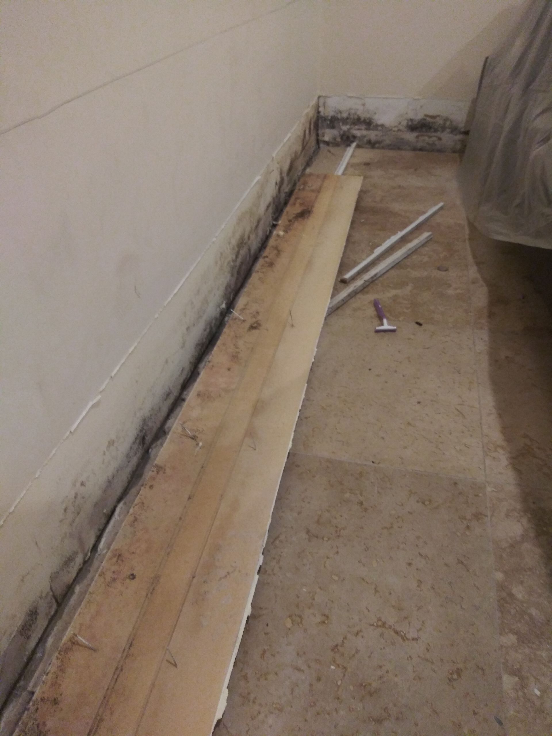 A piece of wood is laying on the floor next to a wall.