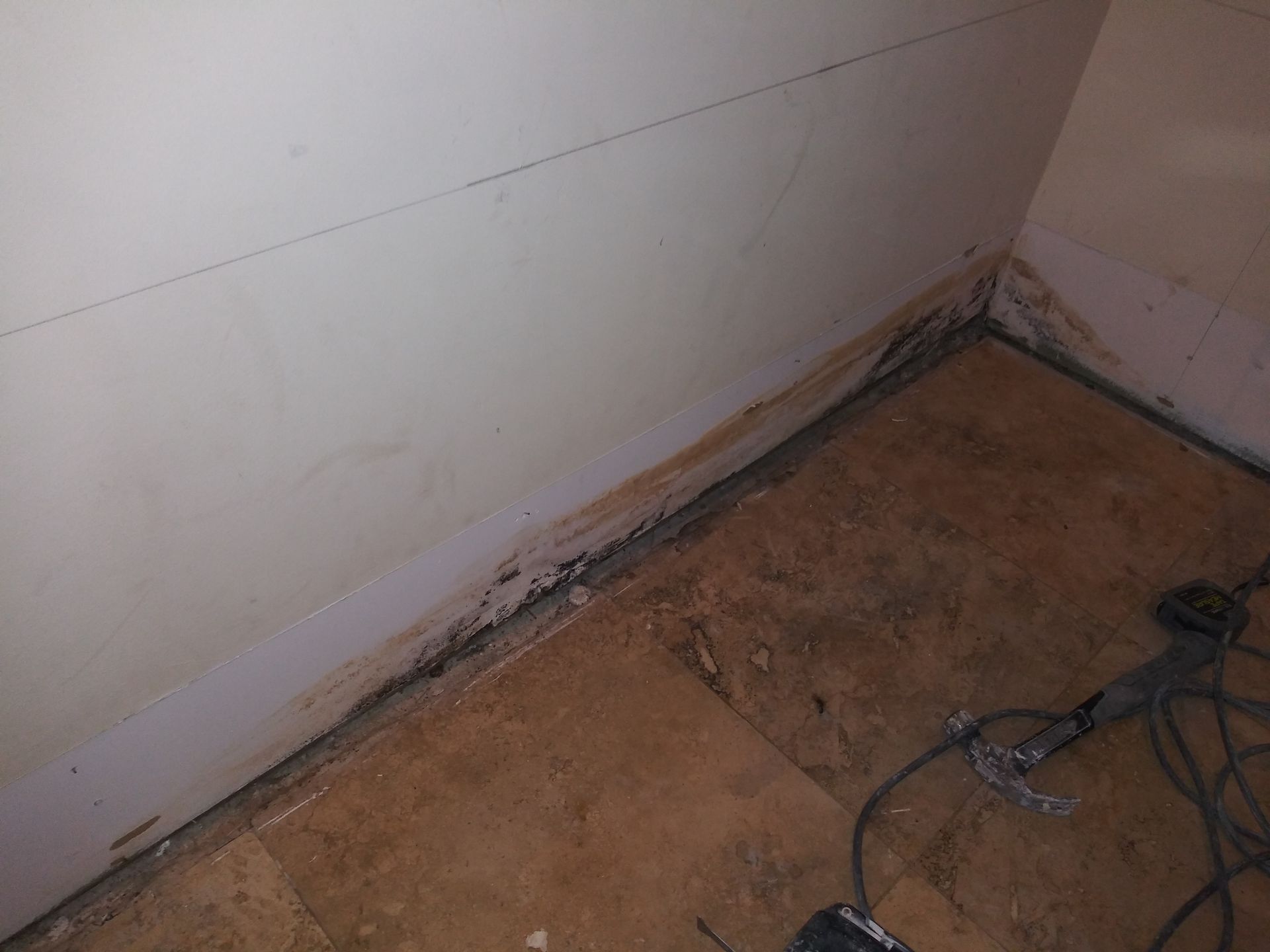 A room with a dirty floor and a white wall.