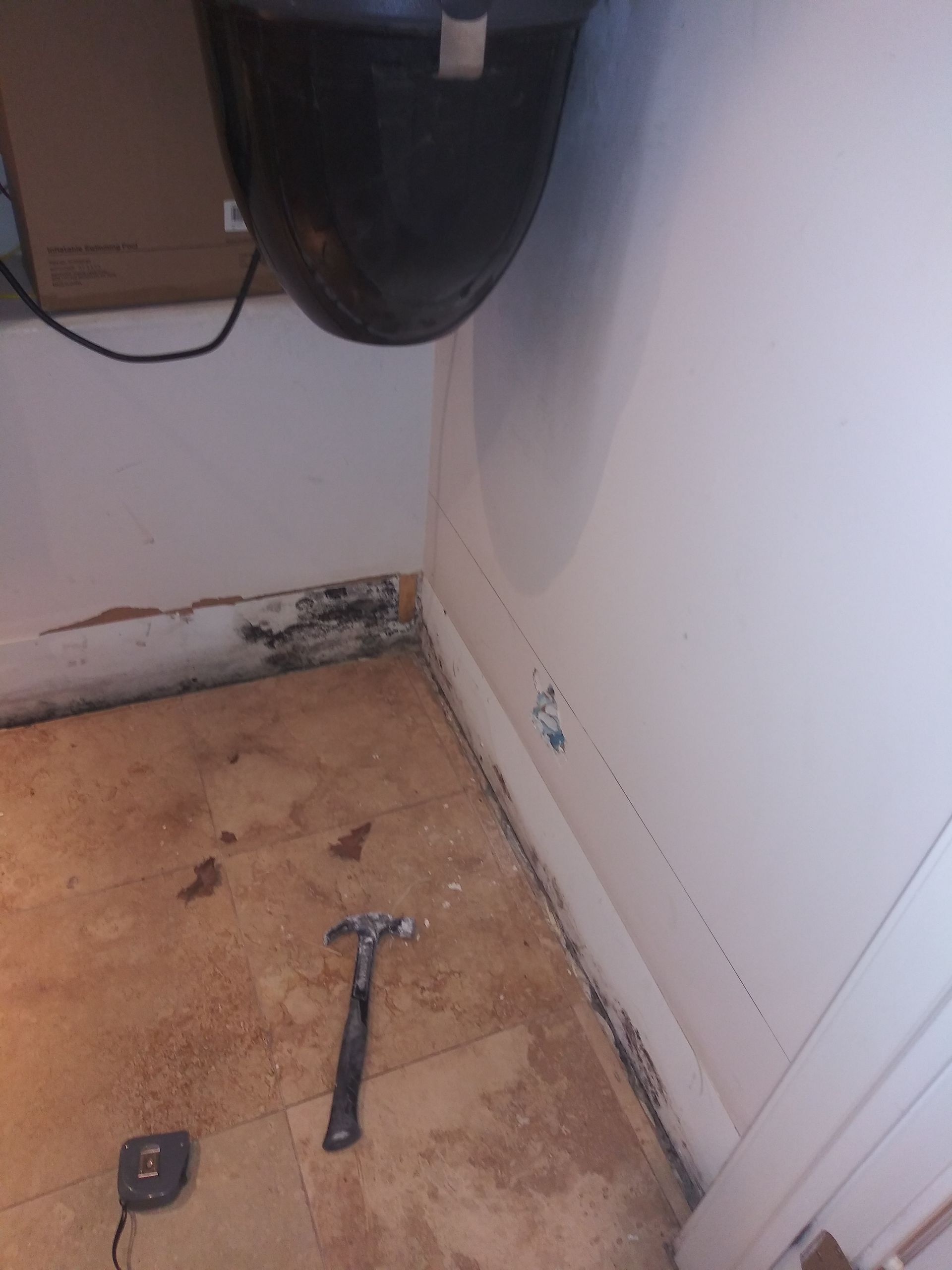 A hammer is laying on the floor next to a tape measure