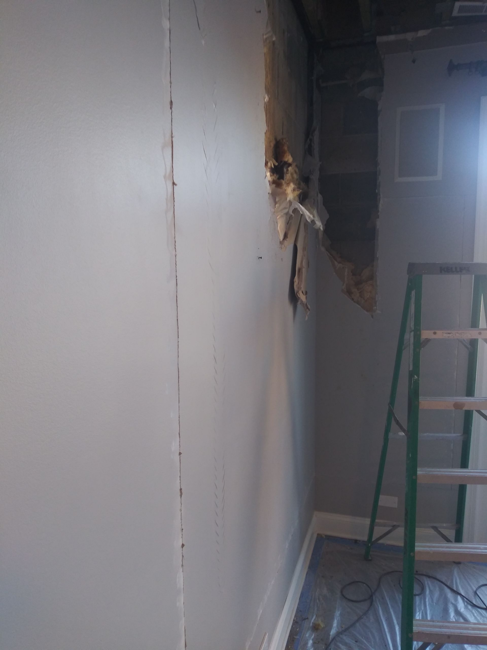 A room with a ladder and a hole in the wall.