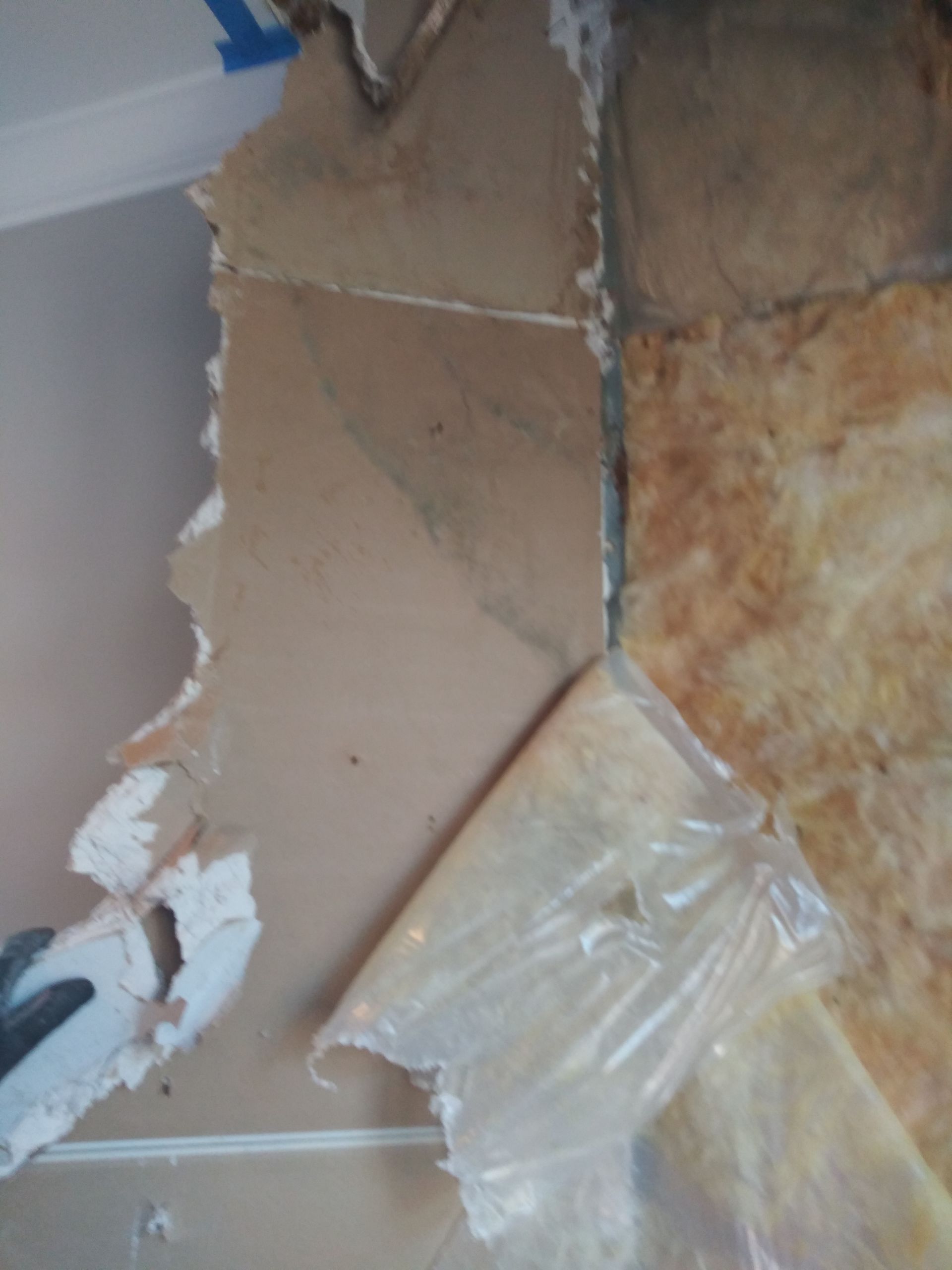 A person is cutting a piece of plastic on a tile floor.