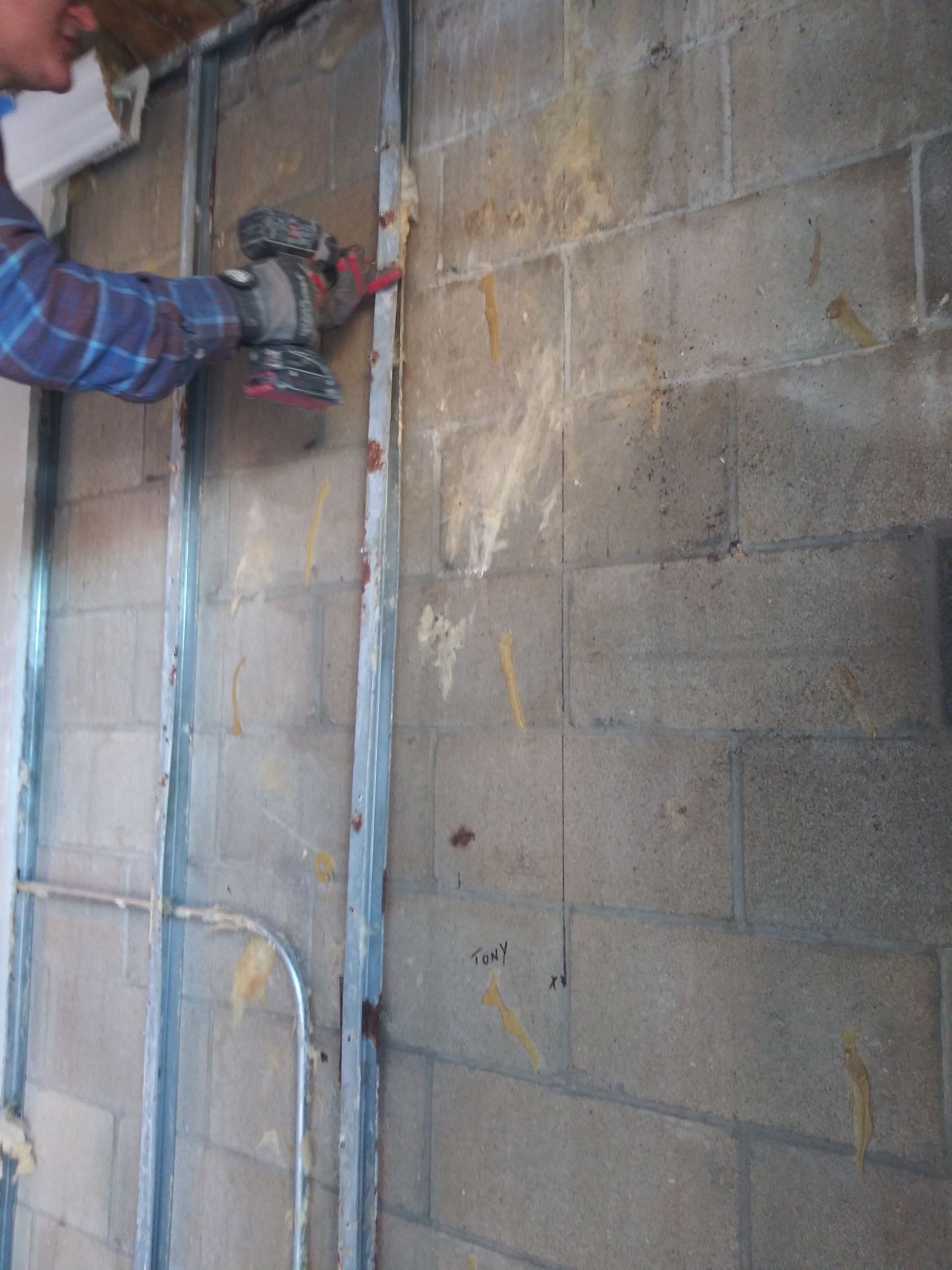 A man is working on a brick wall with a drill.