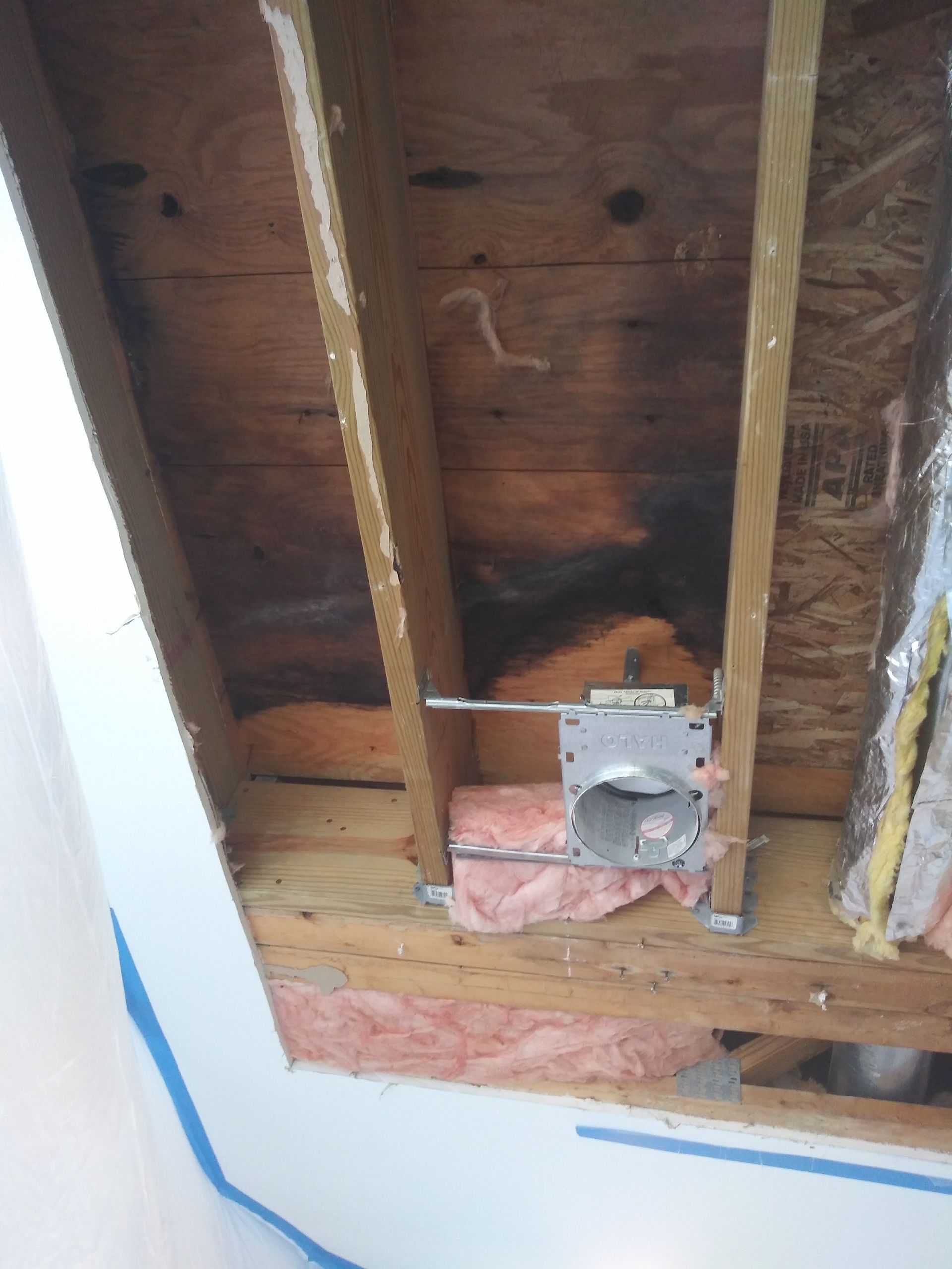 A hole in the ceiling of a building with a electrical outlet in it.