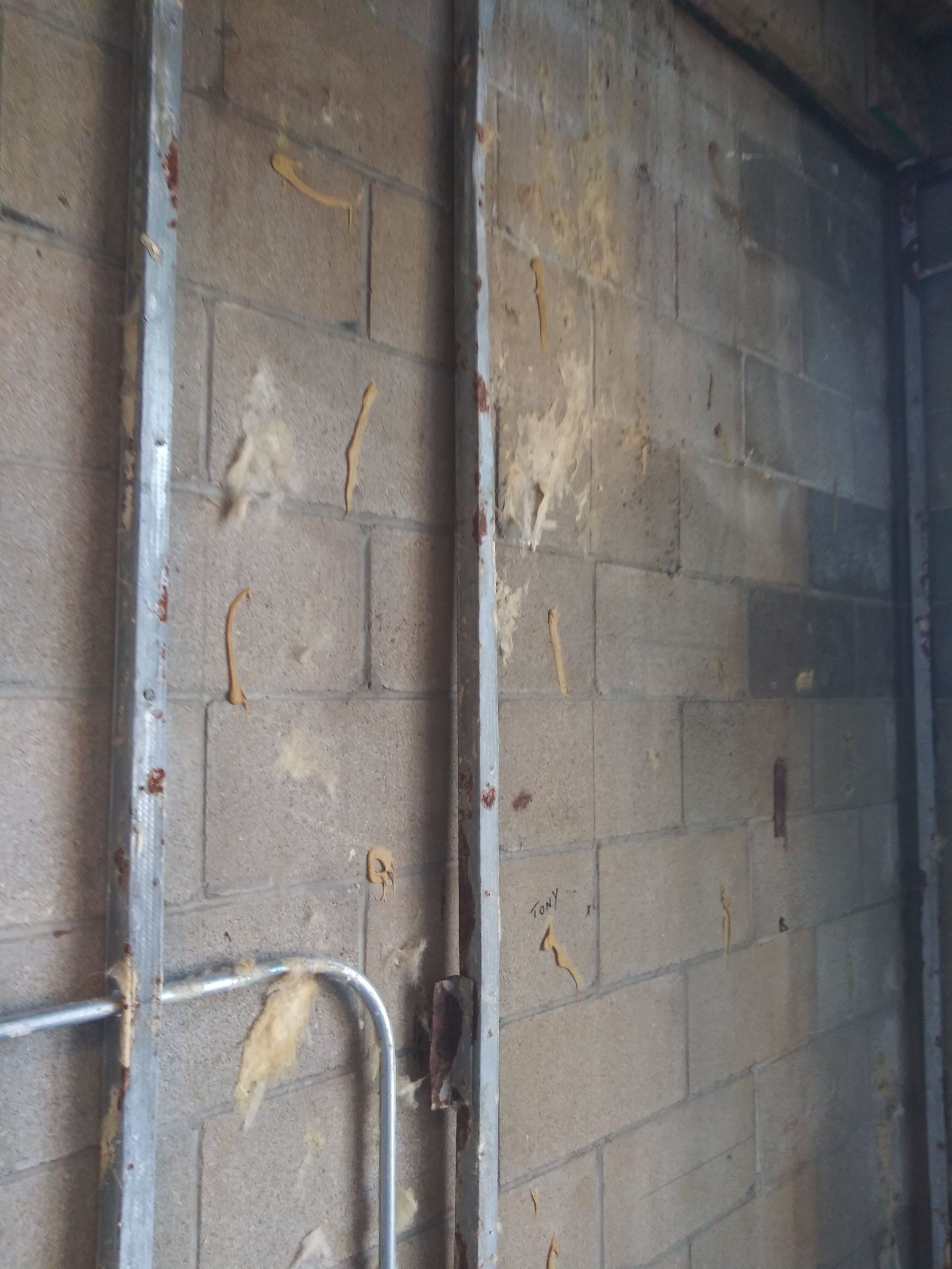 A brick wall with a metal pipe going through it